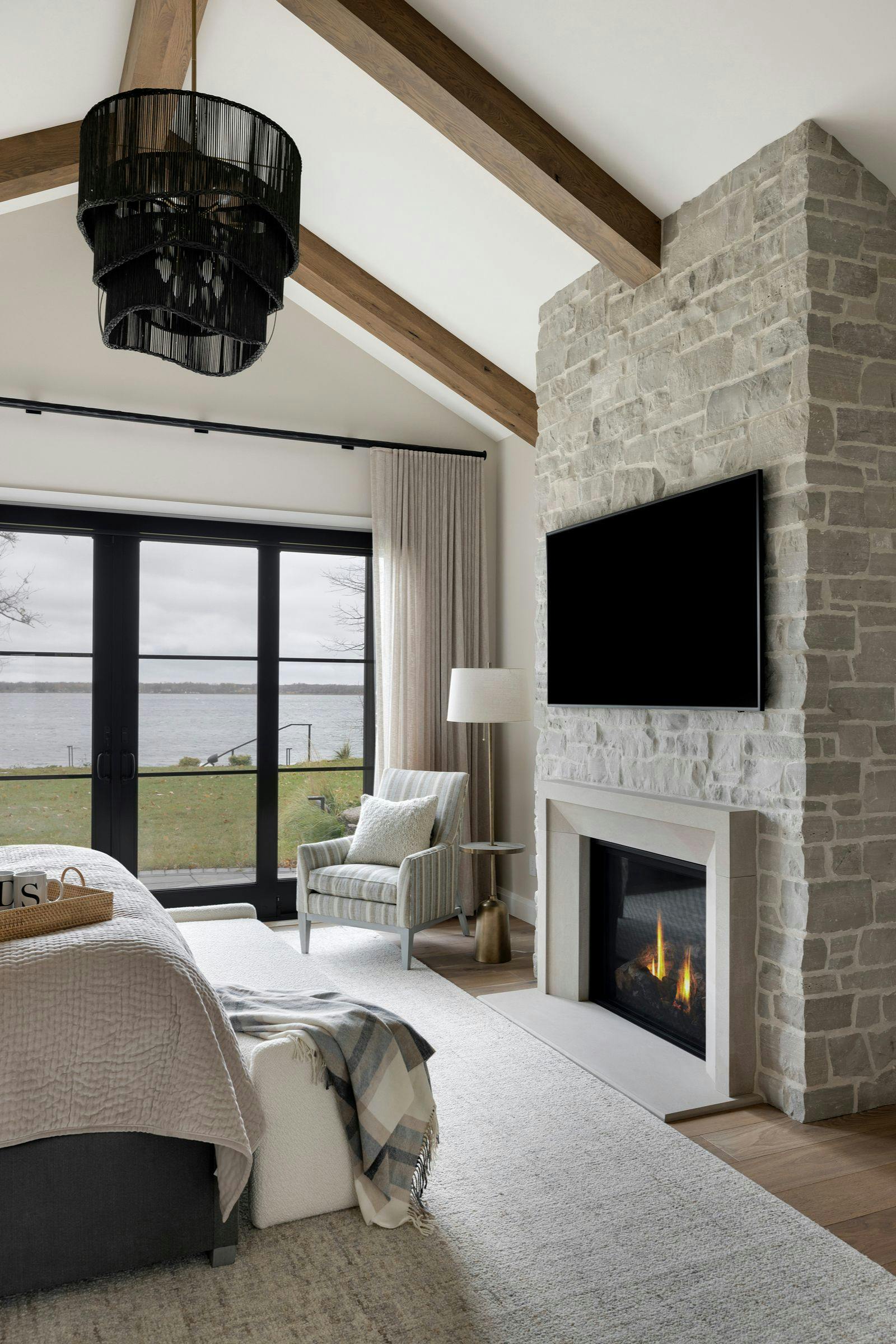 stacked stone fireplace with a tv mounted, vaulted ceilings with beams