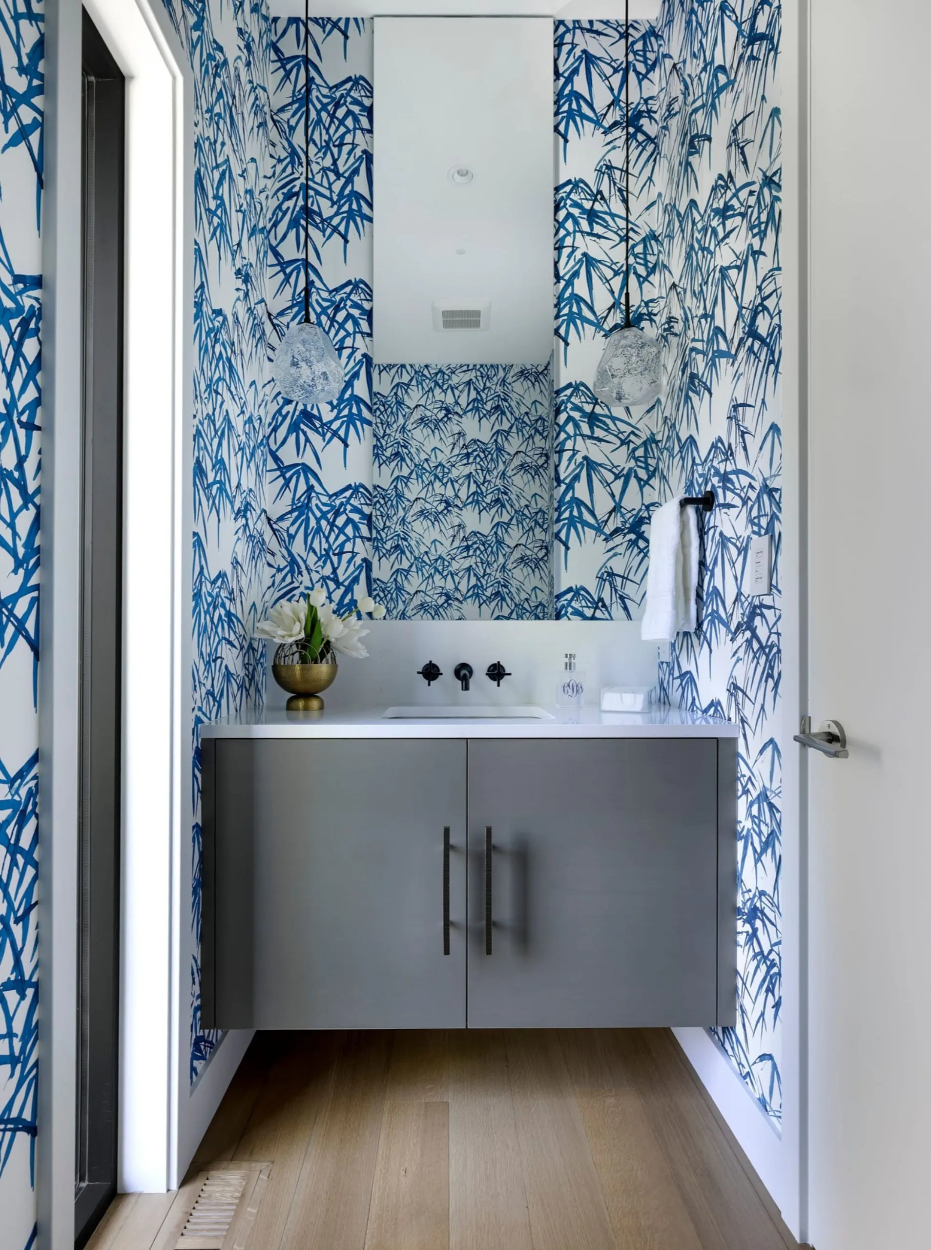 Powder room interior design featuring patterned wallpaper and curated lighting.