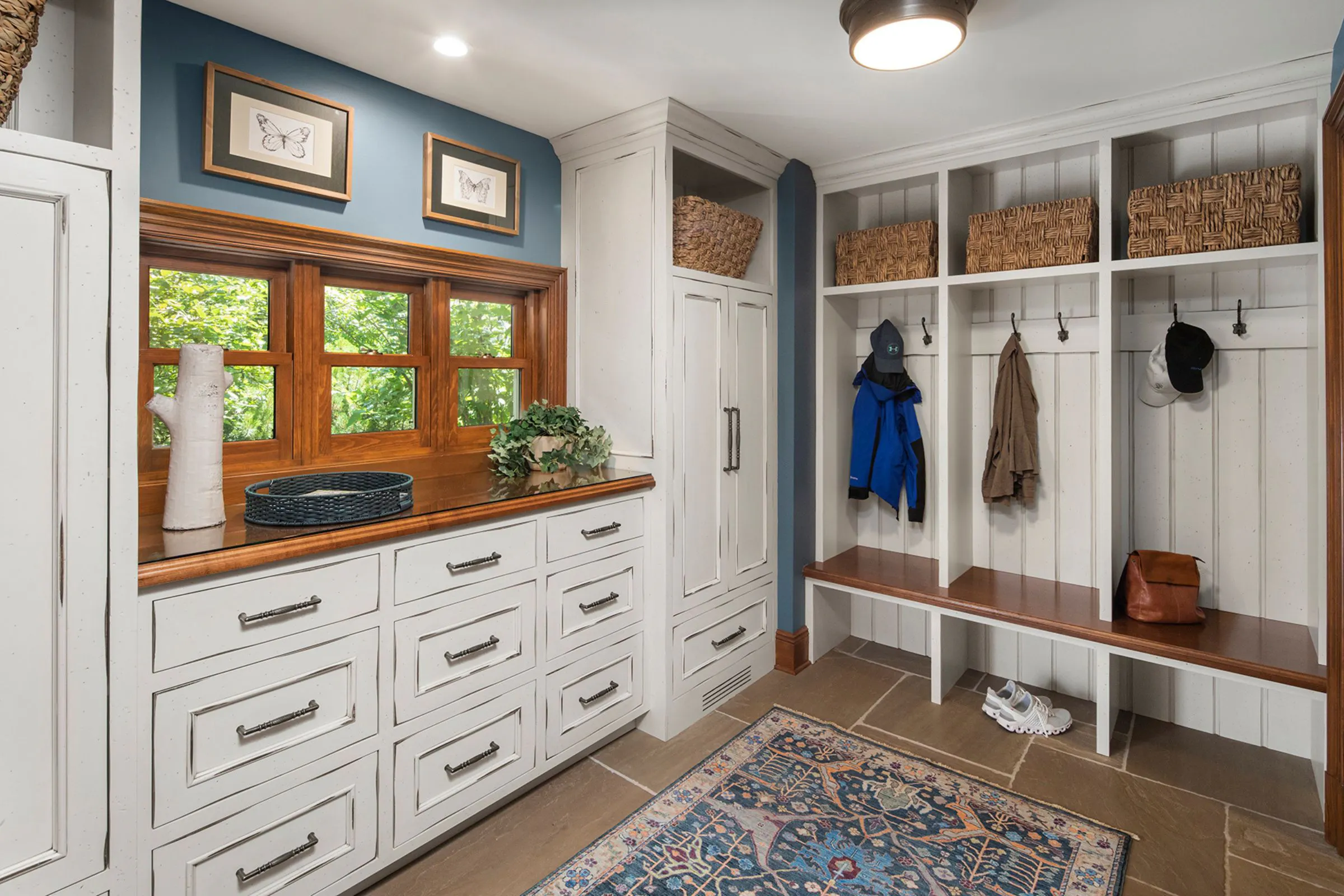 Custom mudroom with wood cabinetry, bench seating, and wall hooks for family storage