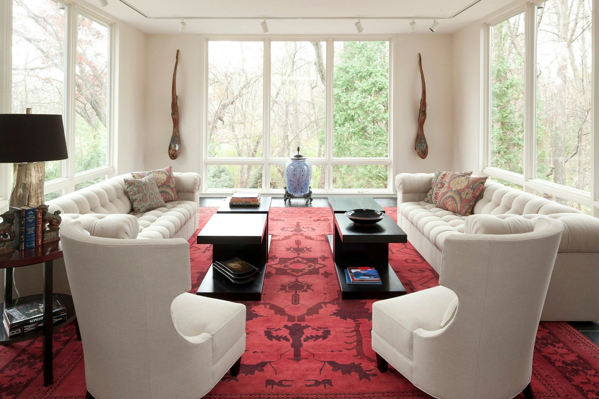 bright living space to entertain, large windows, two couches, chairs, red rug
