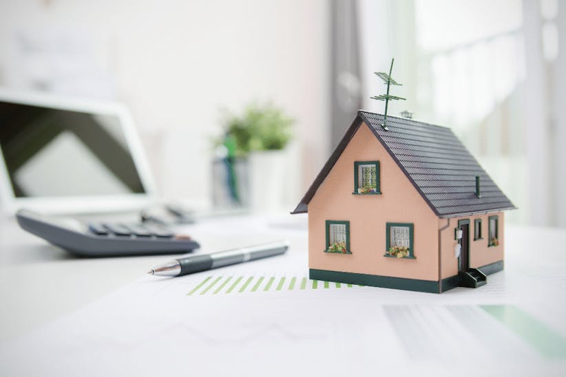A picture of a caluclator, a pen and a wooden house