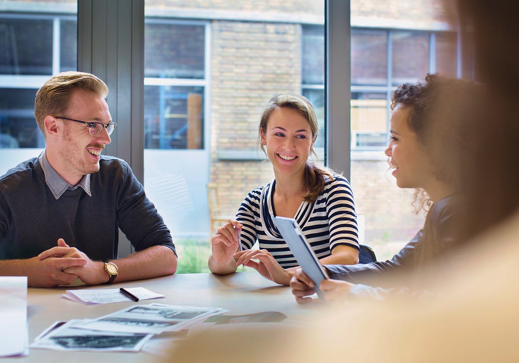 Group of people sat at a desk smiling and discussing their project