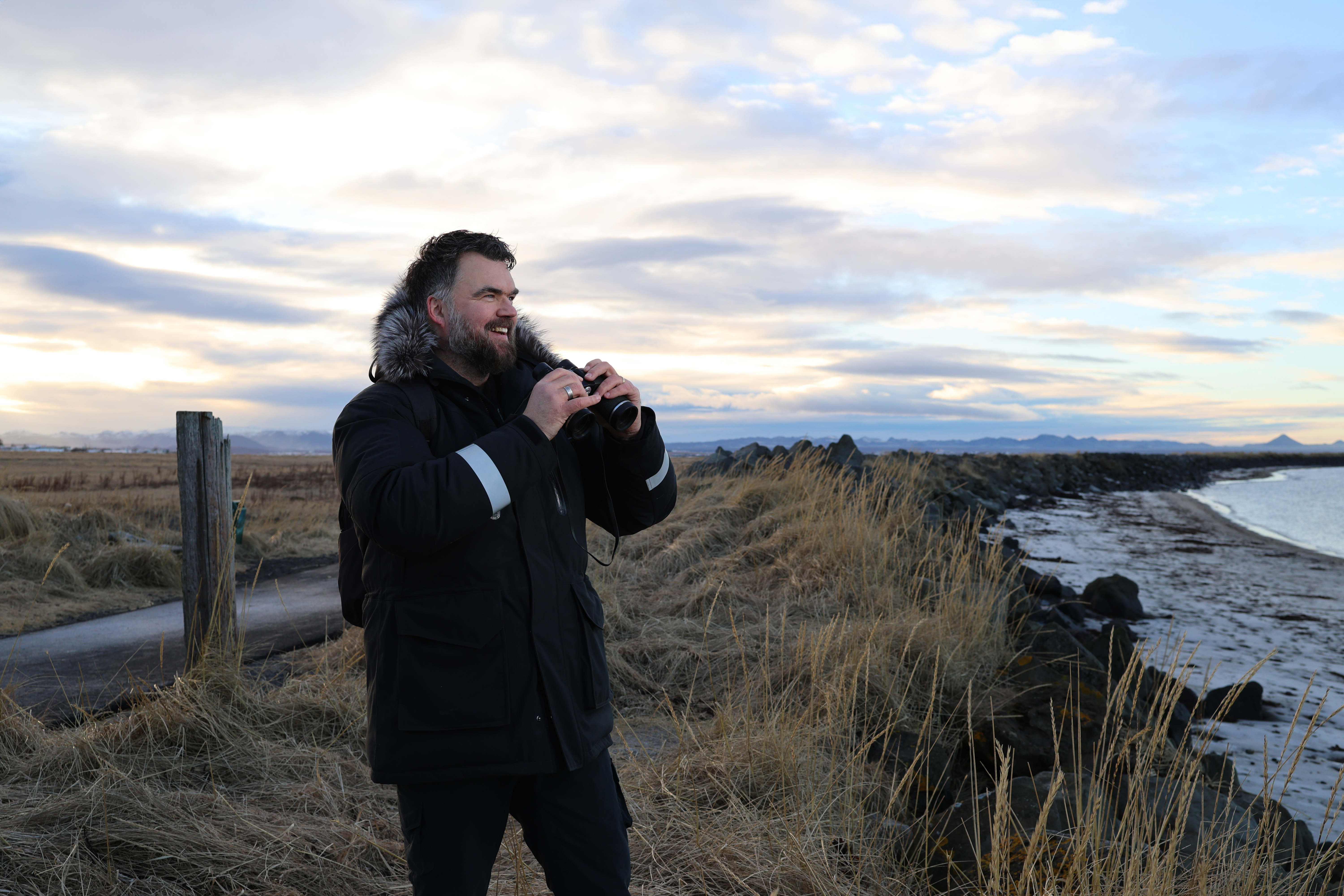 Mynd af nemenda í leiðsögunáminu, hann heldur á kíki og er að horfa á umhverfið í kringum sig