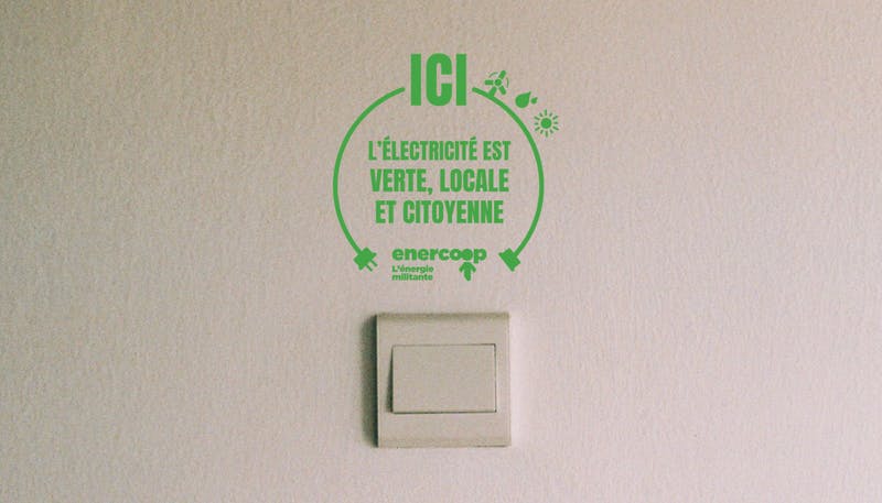 Autocollant collé au dessus d'une prise avec écrit "ici l'électricité est verte, locale et citoyenne"