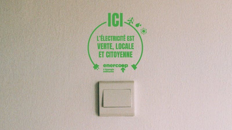 Autocollant collé au dessus d'une prise avec écrit "ici l'électricité est verte, locale et citoyenne"