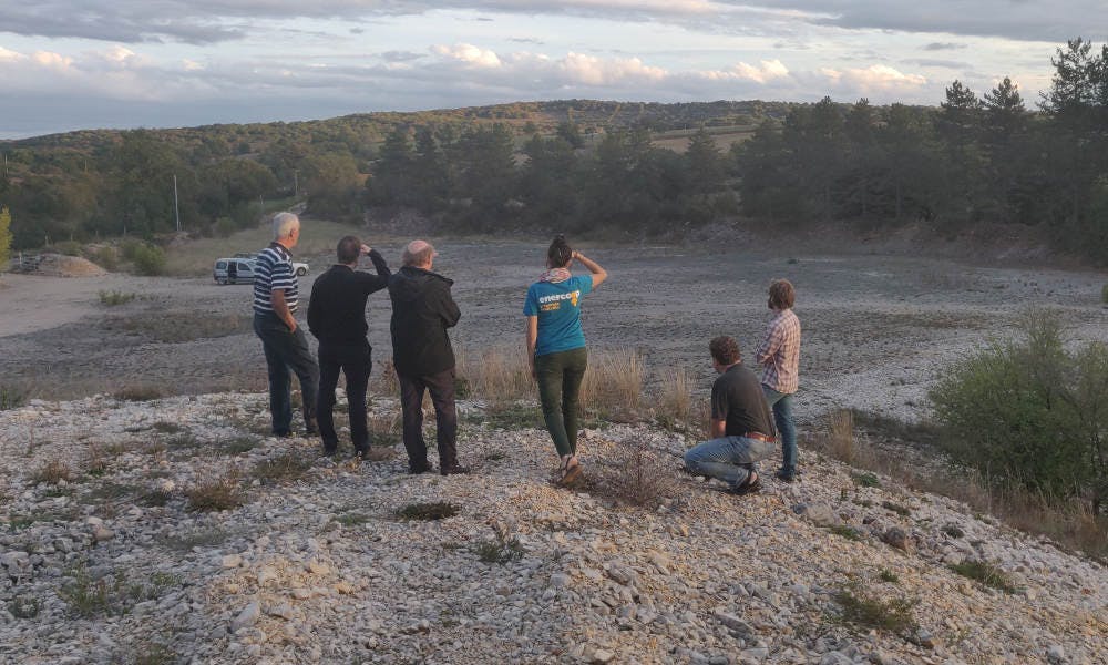 Personnes observant le terrain du futur parc solaire de Combel-Rimat à Blars, par Enercoop Midi-Pyrénées