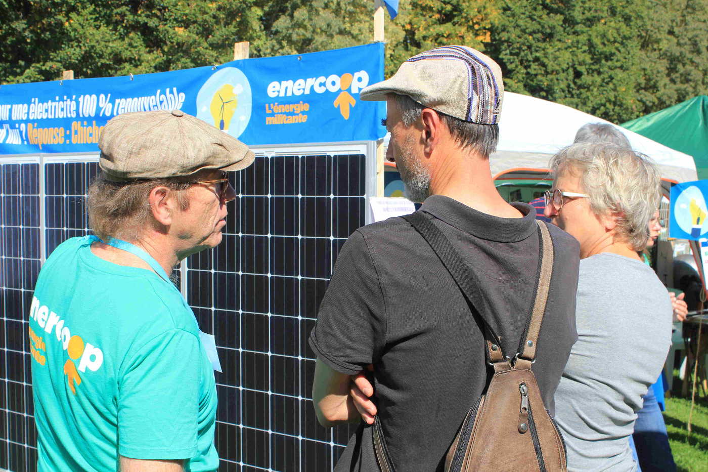 3 personnes discutent devant un panneau photovoltaïque Enercoop