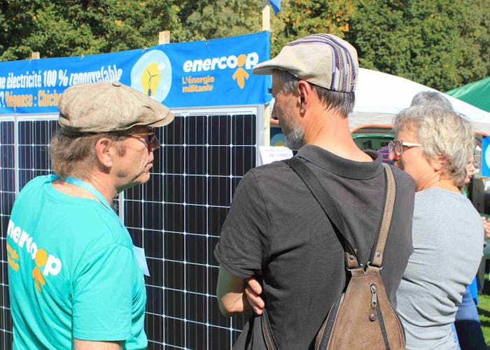 3 personnes discutent devant un panneau photovoltaïque Enercoop