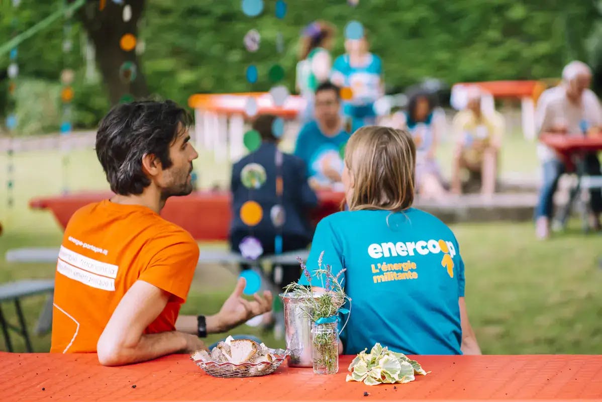 deux personnes de dos à table qui parlent On distingue le Tshirt Enercoop