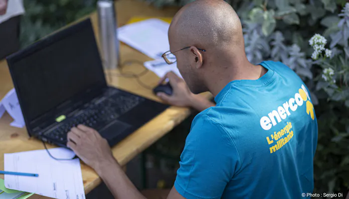 personne avec un t-shirt Enercoop travaillant sur un ordinateur portable