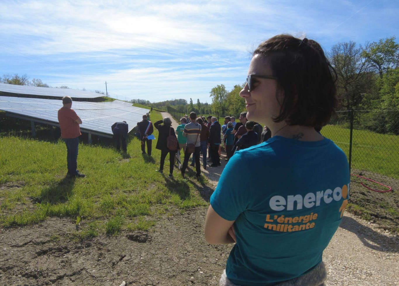 Photo d'une visite du parc photovoltaïque de Faurilles. On y voit au premier plan une salariée Enercoop Nouvelle-Aquitaine de dos, en second plan un groupe de personne qui observe le parc