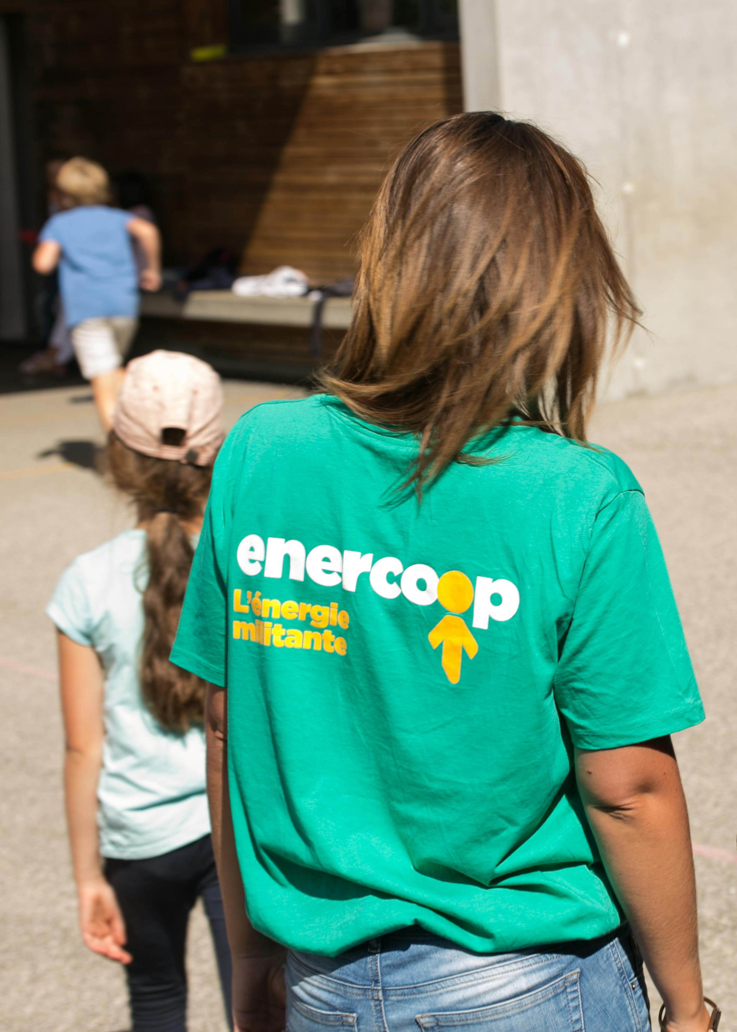 Deux femmes de dos dans une école au sein d'une collectivité. L'une avec un t-shirt vert Enercoop.