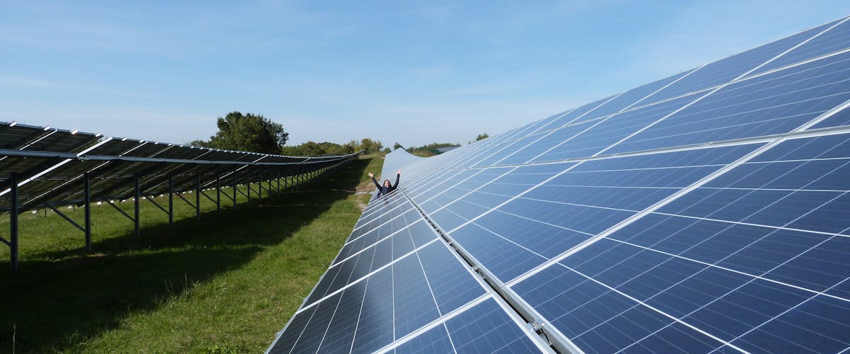 Une personne levant les bras au parc solaire de Pousse-Pisse à Carlus-Le Séquestre / Enercoop Midi-Pyrénées