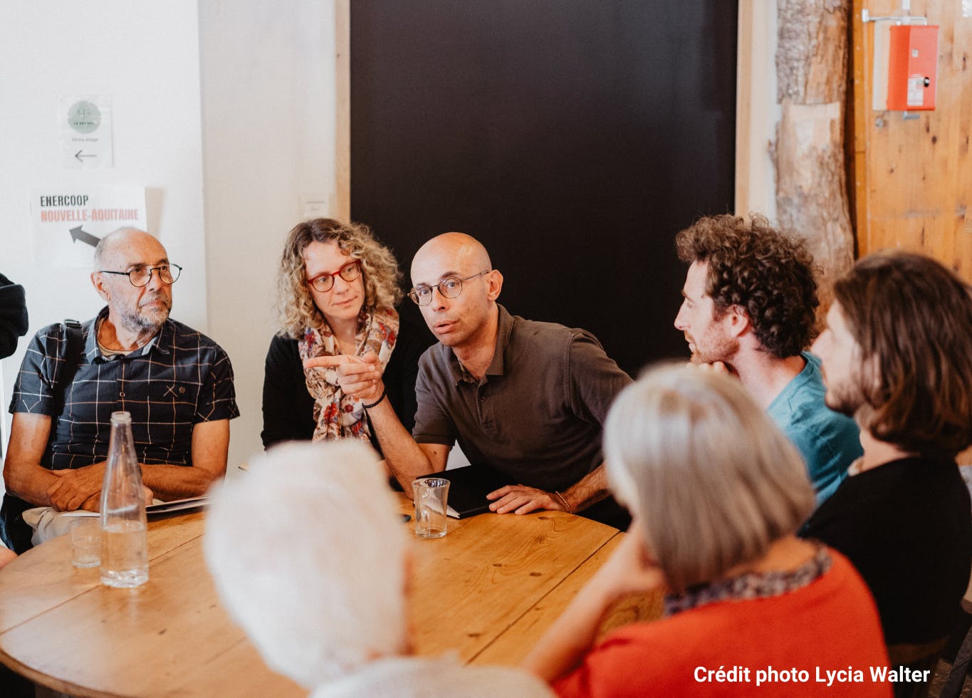Photo d'un groupe de sociétaire Enercoop Nouvelle-Aquitaine qui discutent autour d'une table. Un homme est en train de parler