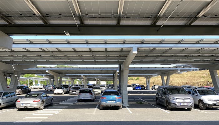 Photo d'un parking où sont stationnées les voitures sous les ombrières de la glèbe