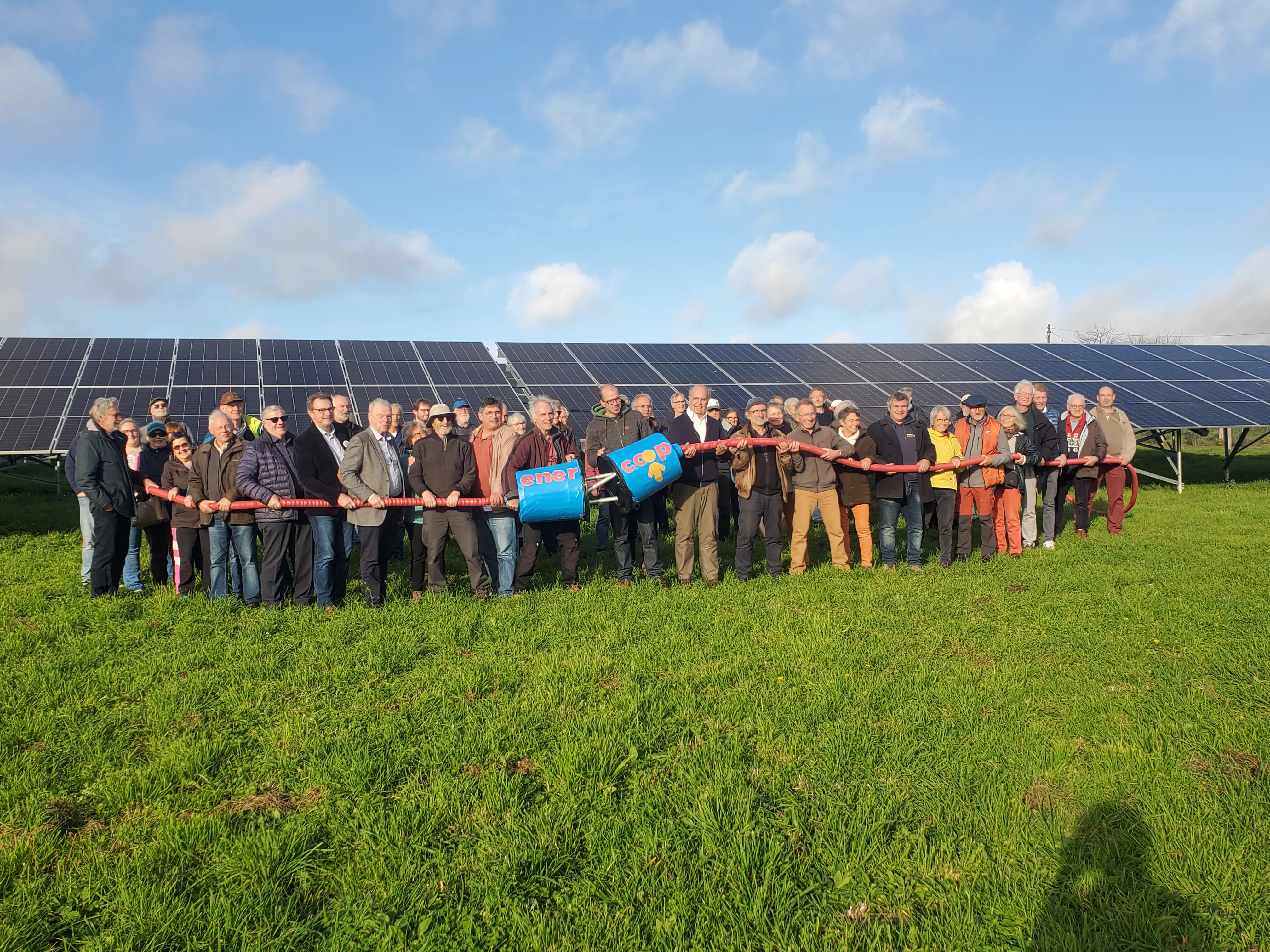 Photo de groupe devant les panneaux solaires avec une prise géante pour symboliser l'inauguration