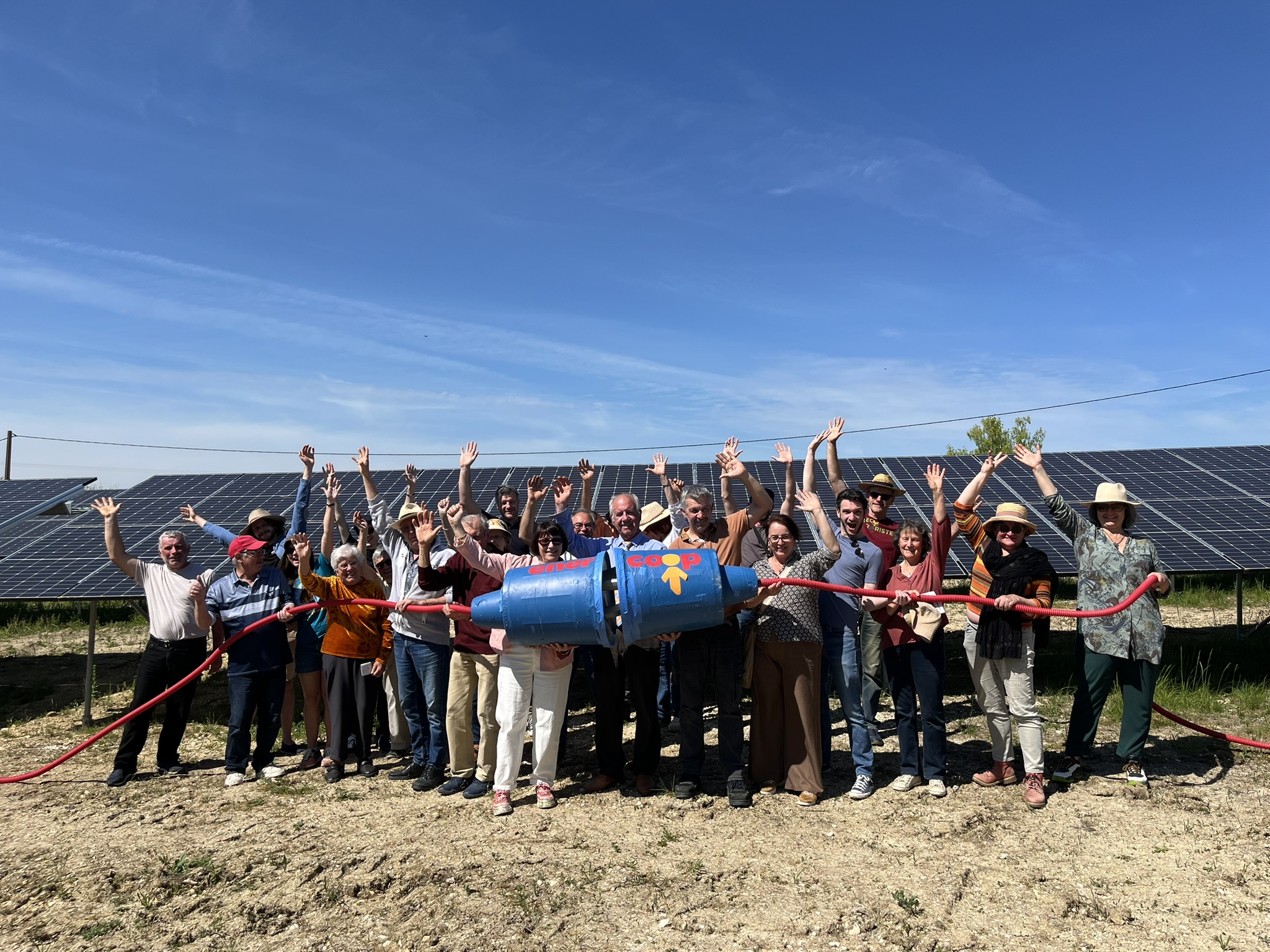 Les participants à l'inauguration posent devant des panneaux solaires avec une prise électrique géante