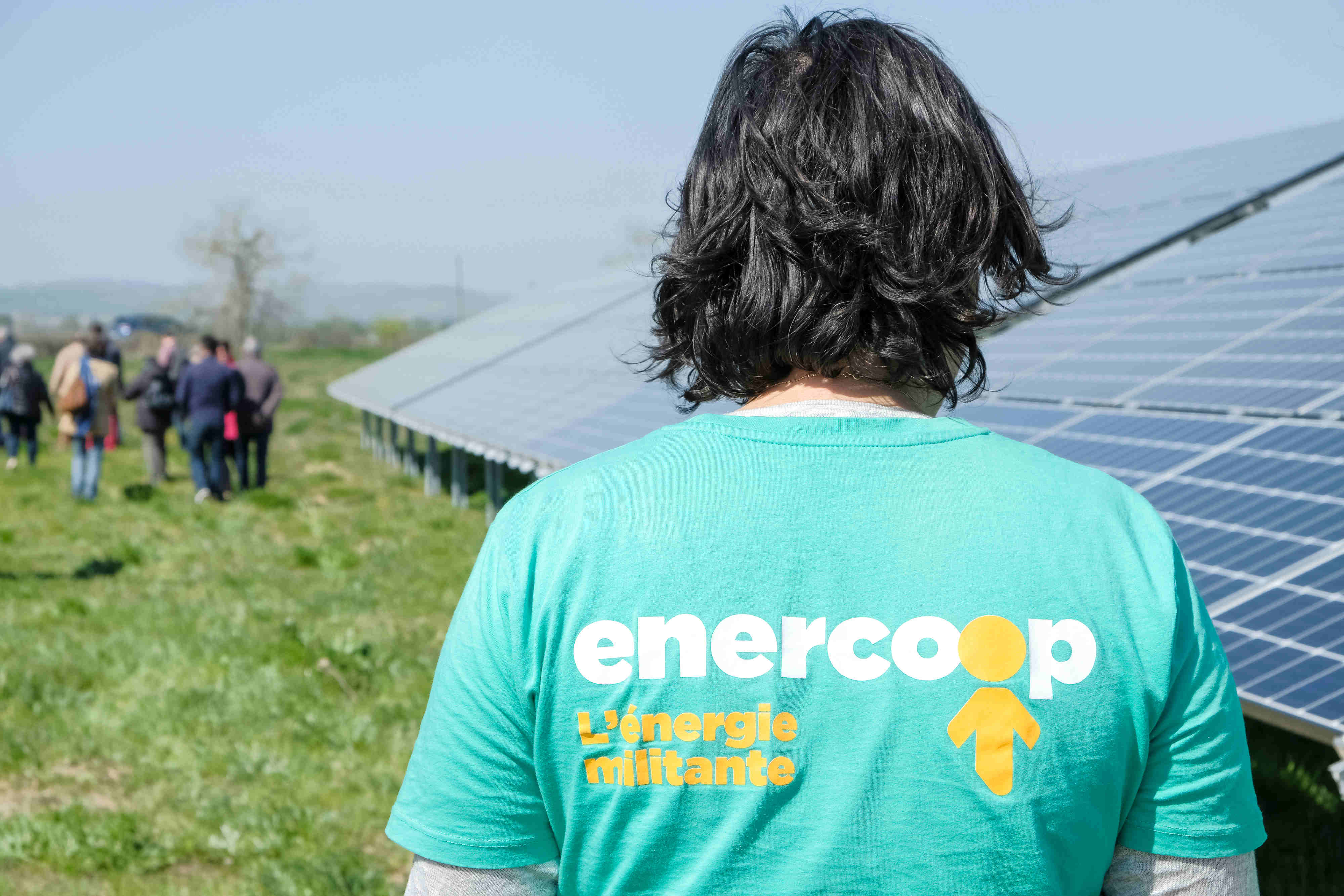 Photo d'une personne de dos avec un tee-shirt Enercoop dans un parc solaire - credit Arthur Perset