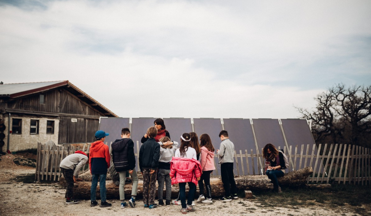 Enfants de dos écoutant une guide lors d'une classe découverte aux Amanins