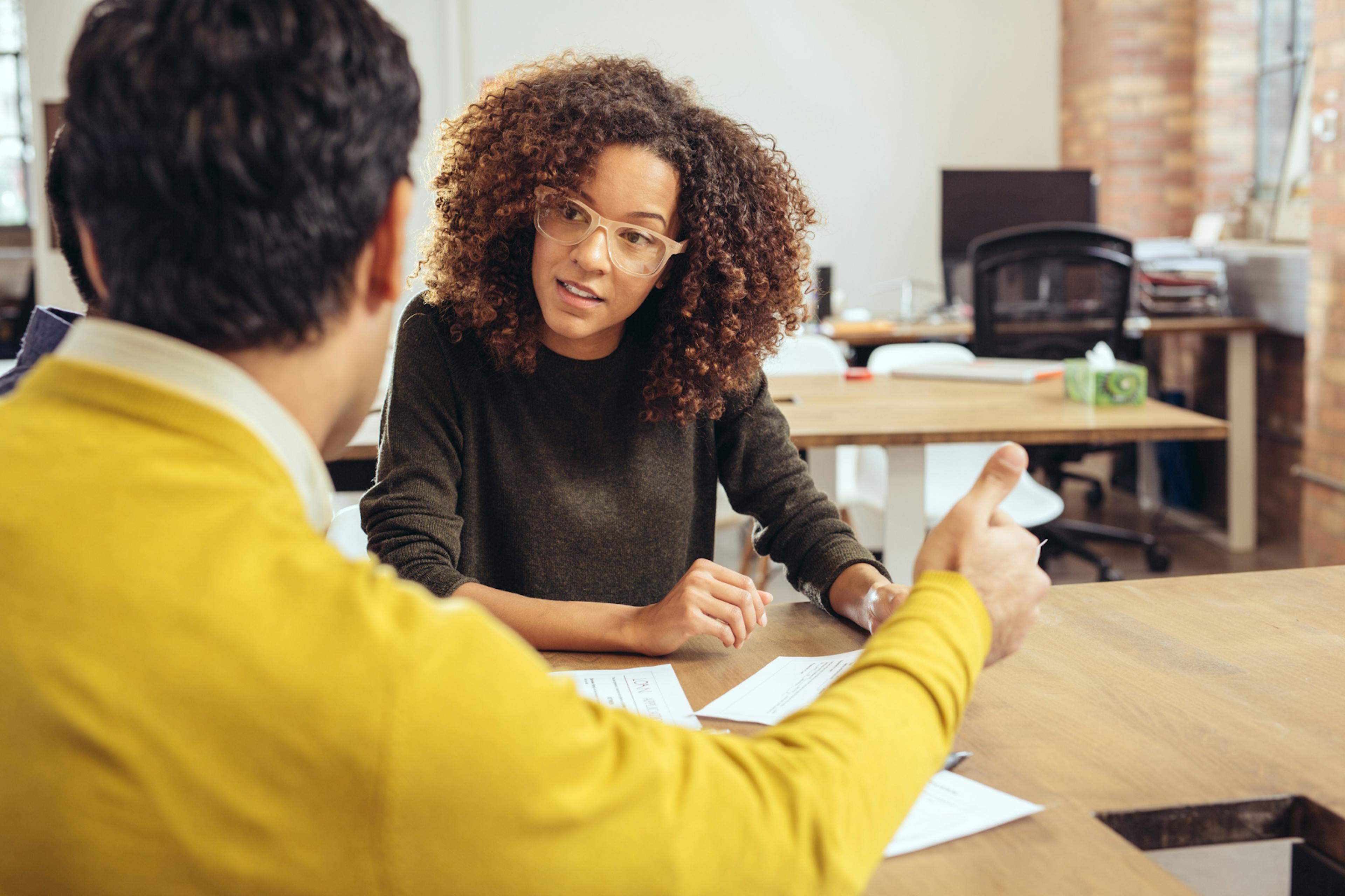 Two people sitting at a wood table consulting about taxes.