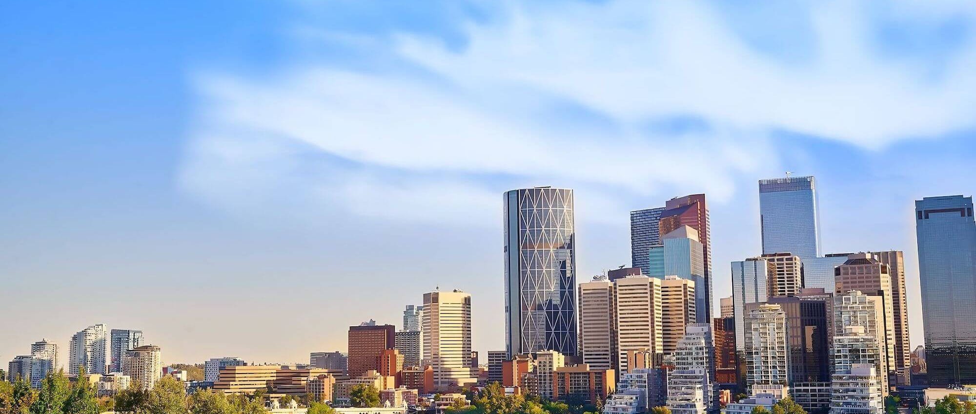 Calgary skyline under a blue sky, centered on the Bow Tower.