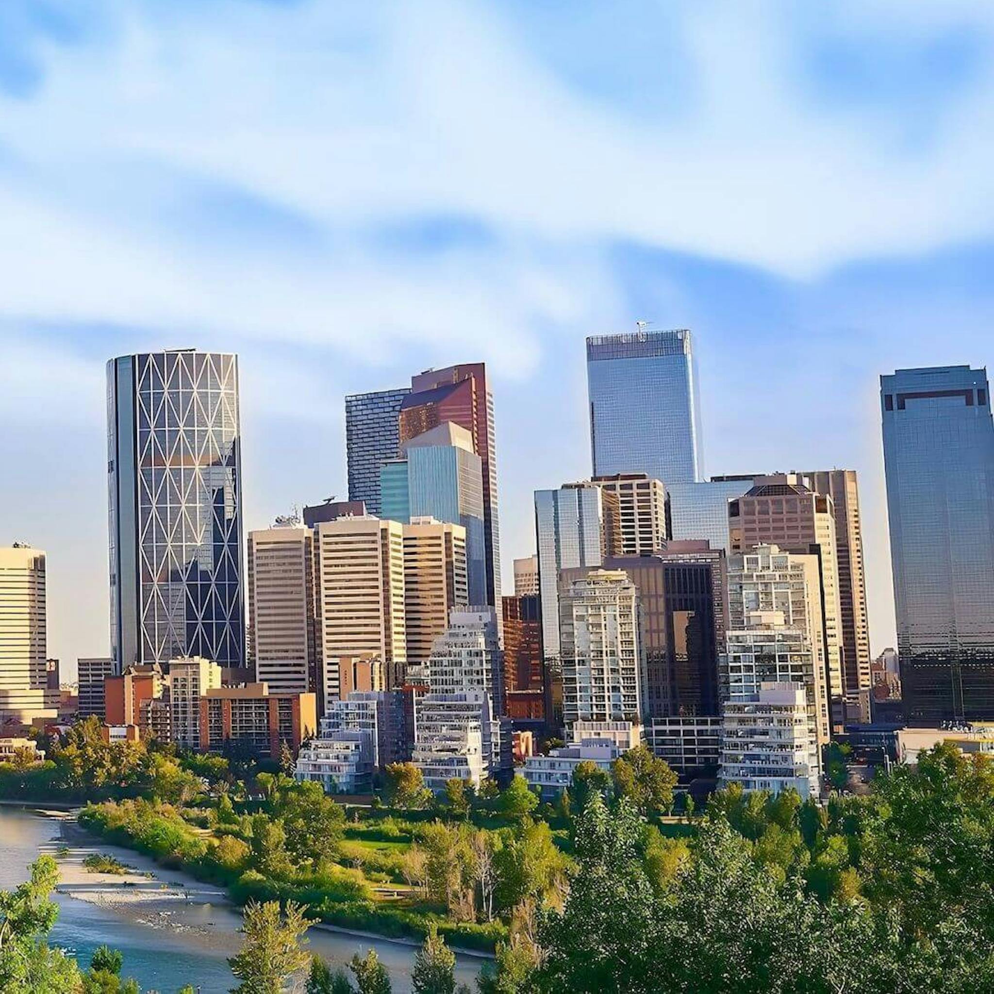 Calgary skyline under a blue sky, centered on the Bow Tower.