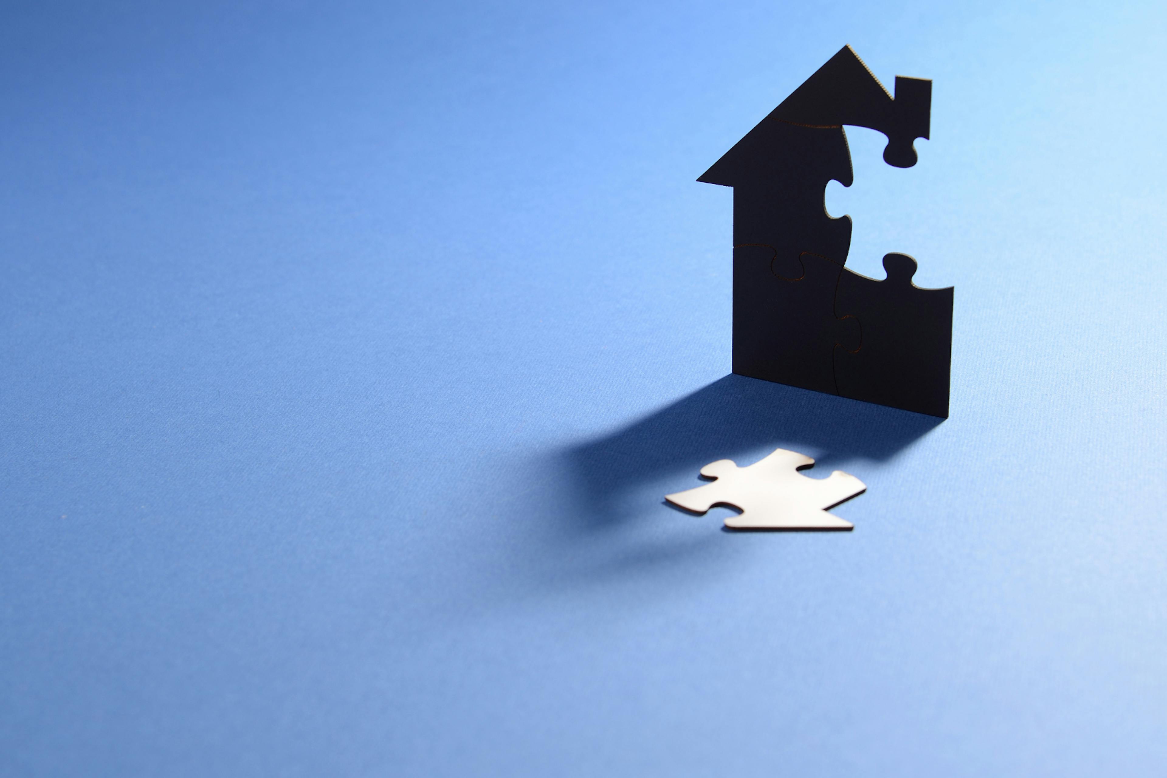 Cutout of a house with the puzzle piece cut out of it.