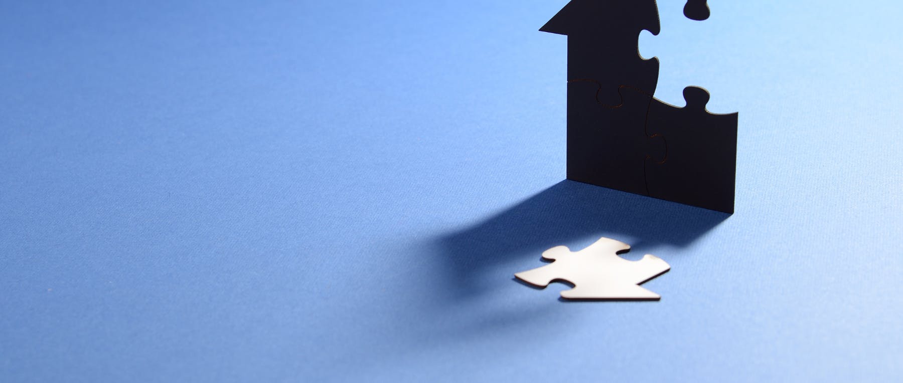 house with a puzzle piece cut out that is laying on a blue background