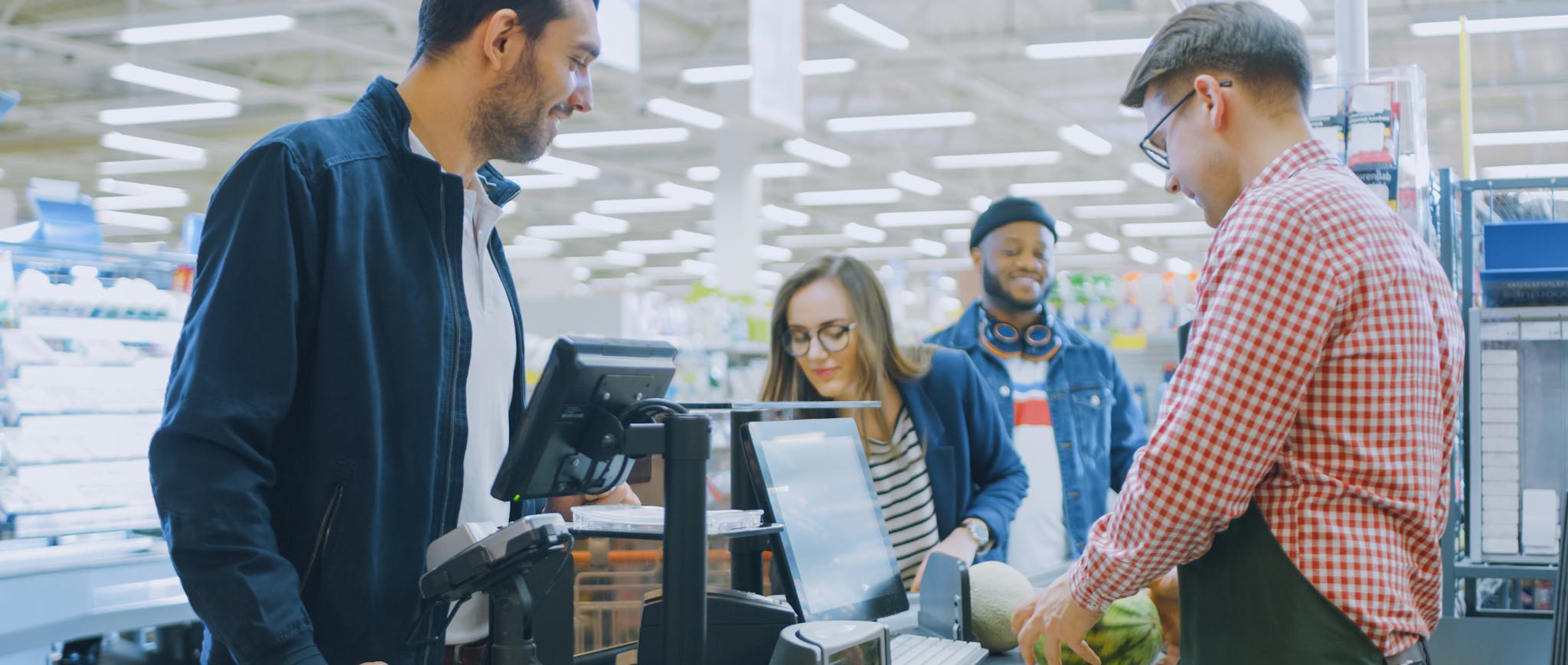 three people in a checkout line at the grocery store