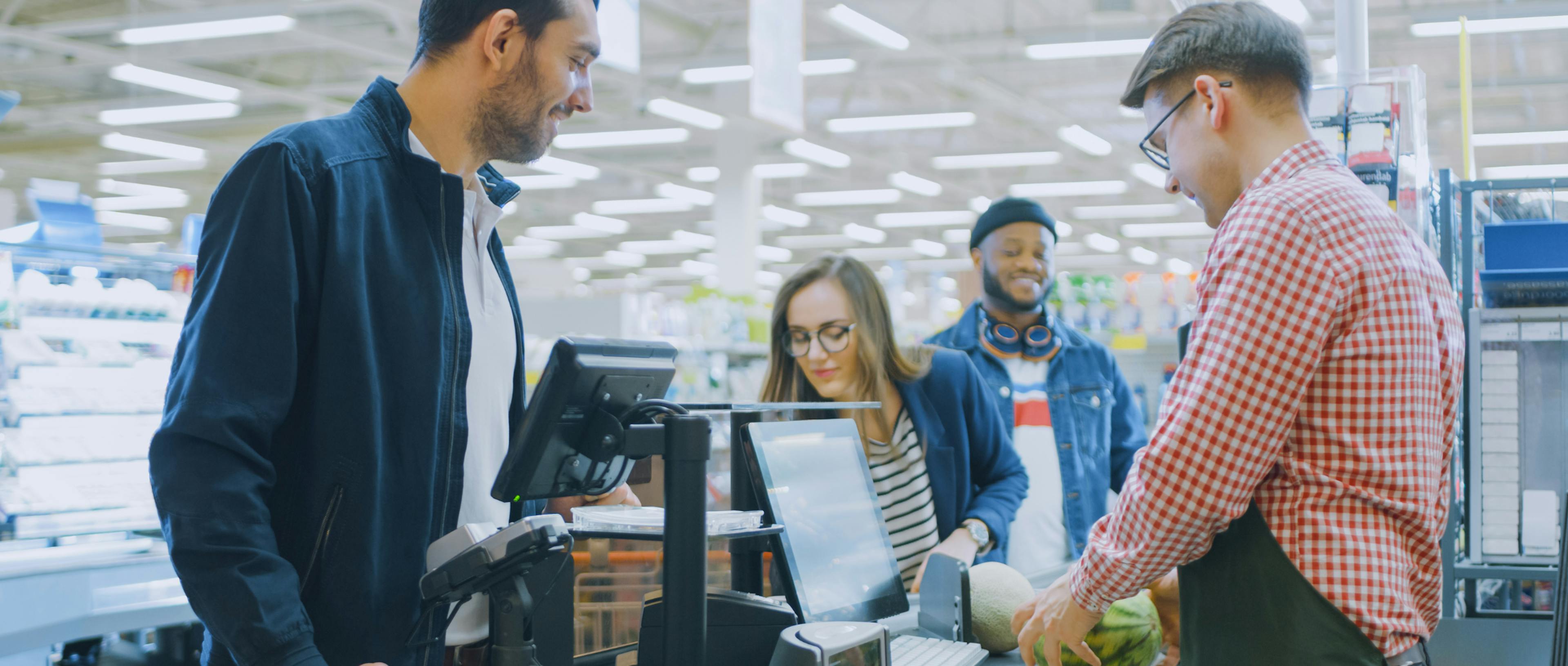 three people in a checkout line at the grocery store