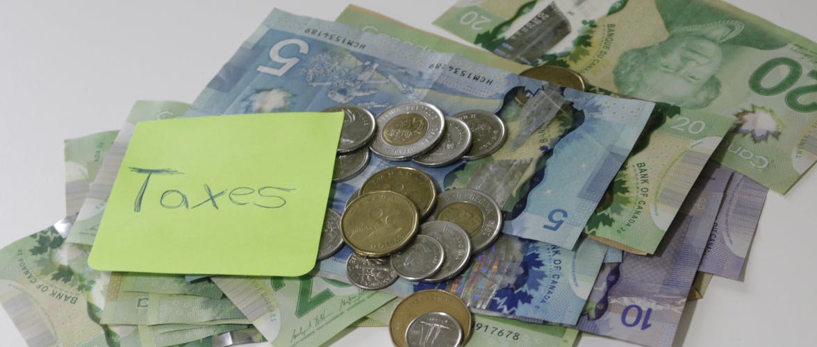 Picture of Canadian money with a note that has 'Taxes' handwritten on it