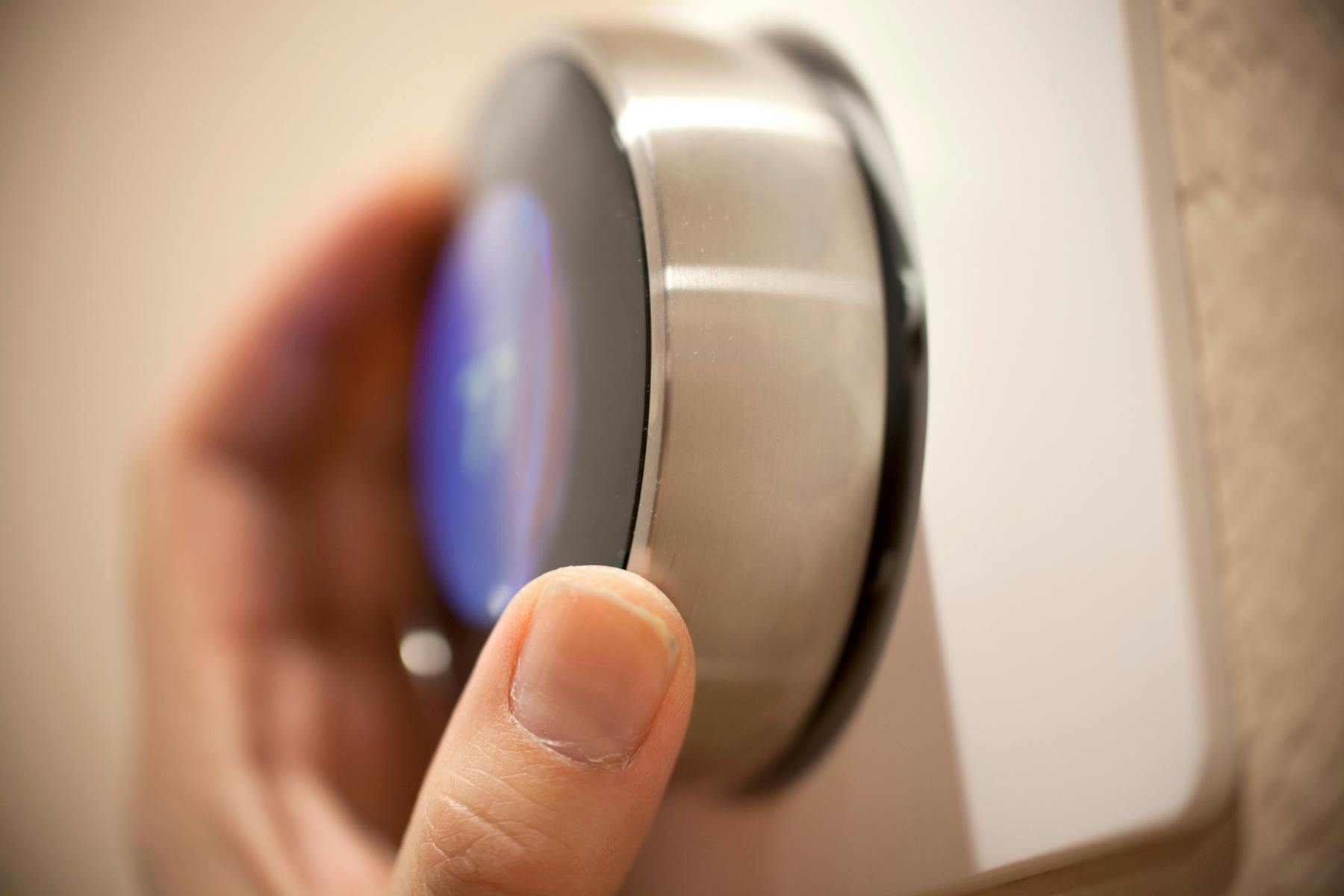 Person adjusting their thermostat