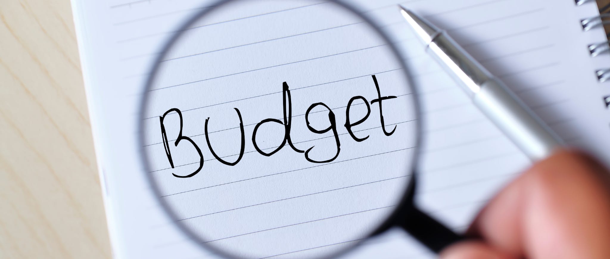 Notebook with budget magnified with a magnifying glass