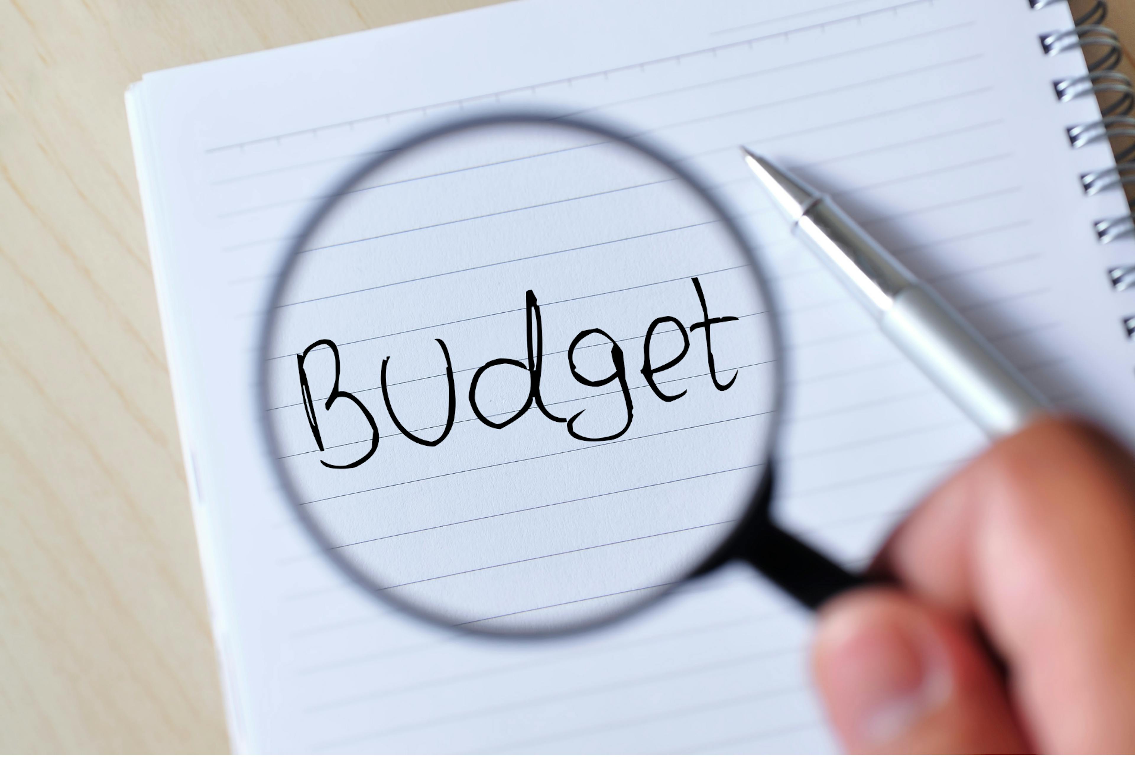 Notebook with budget magnified with a magnifying glass