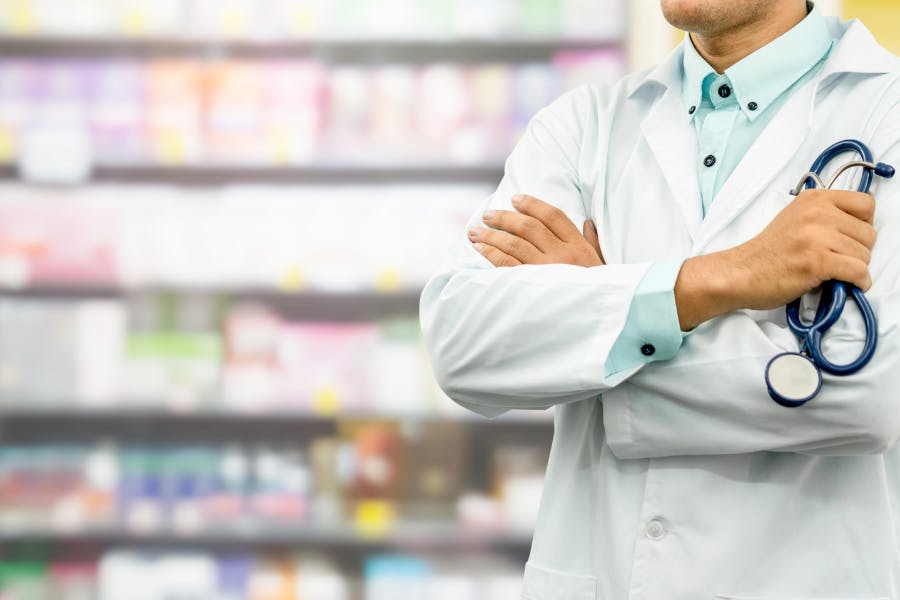 Pharmacist standing in front of shelves of medication