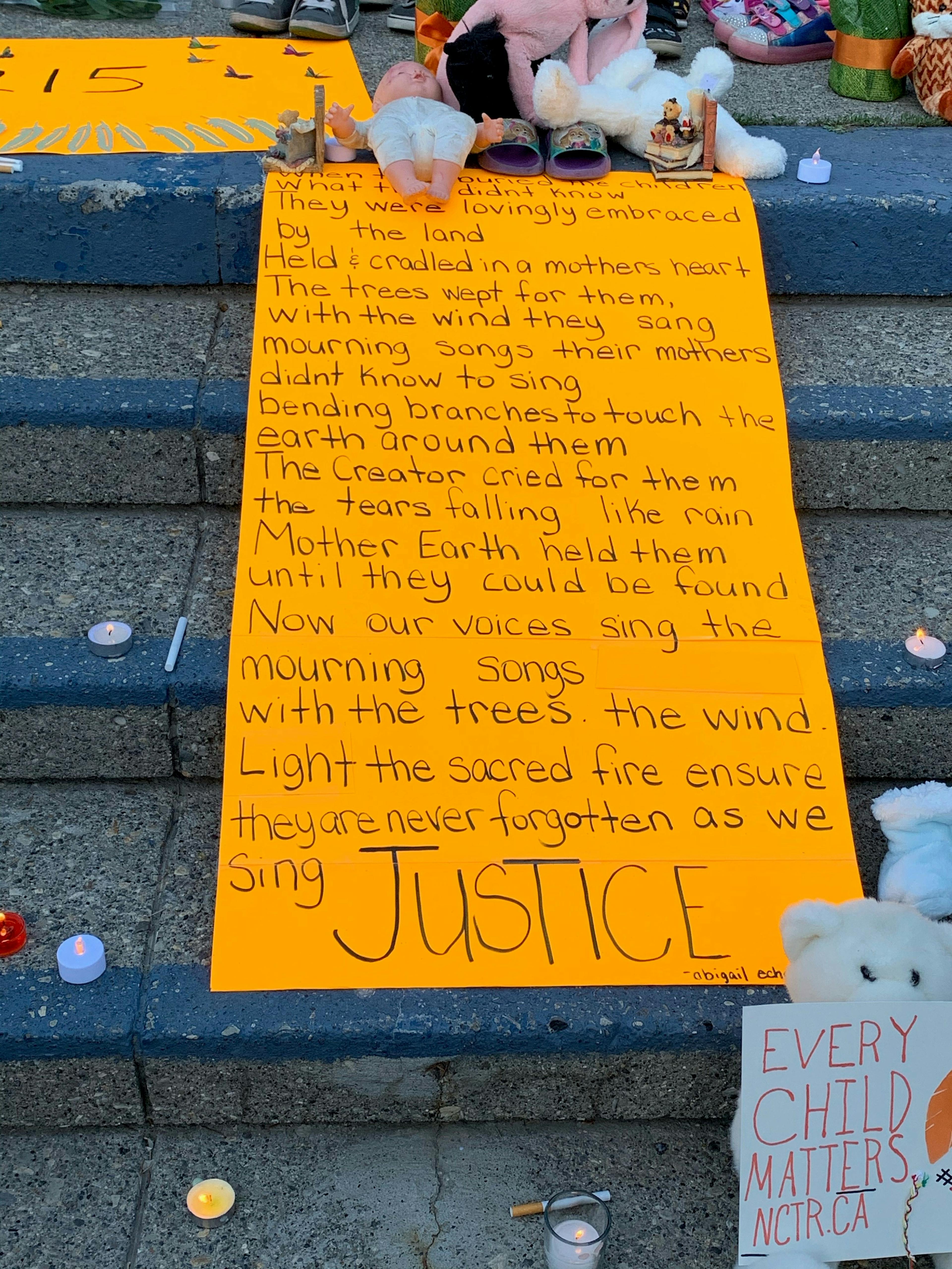 Photo of an orange poster on stairs with messaging about justice for indigenous children and how they lost their lives to residential schools.