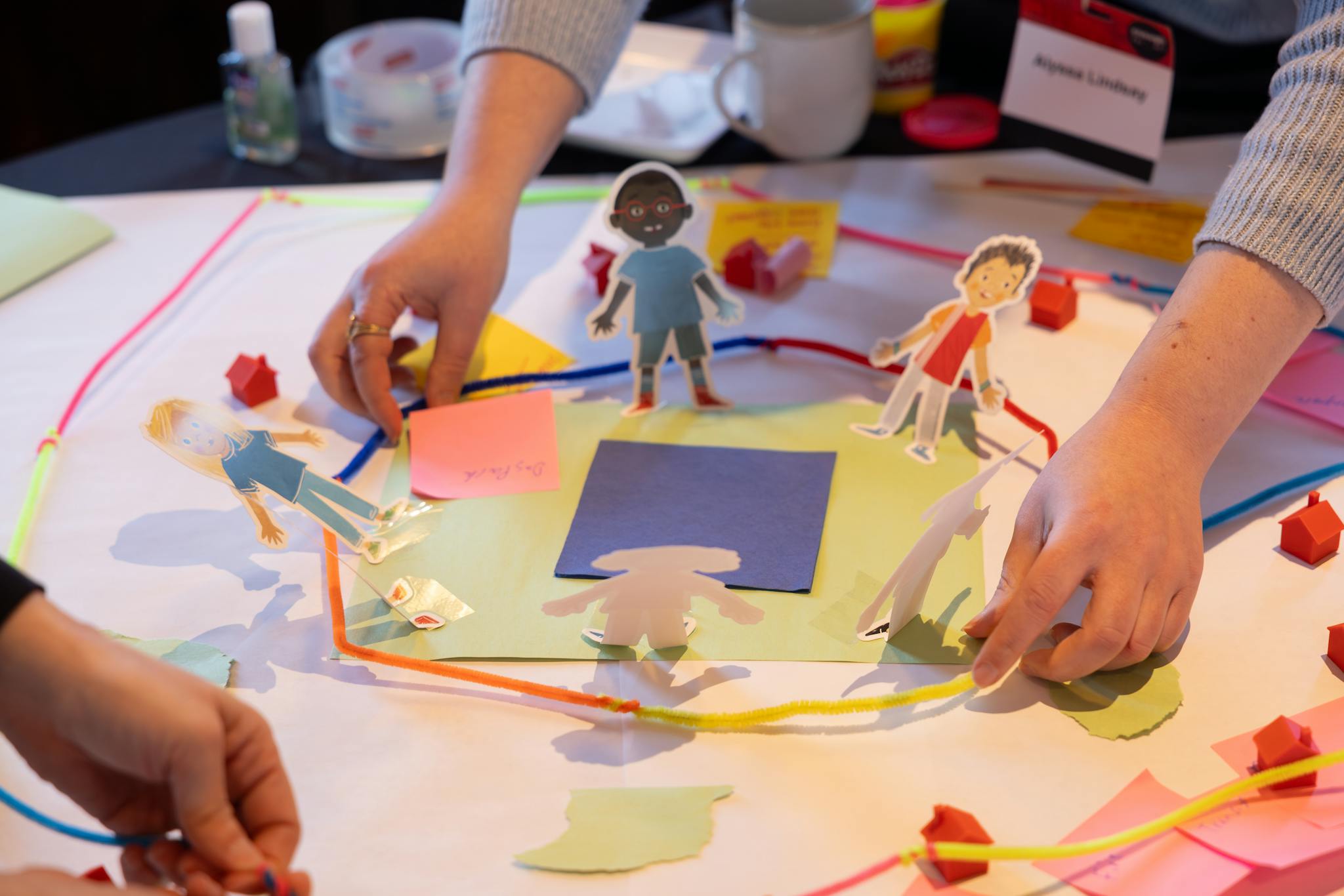 A diagram of a city made from pipe cleaners, pictures of people, and craft paper