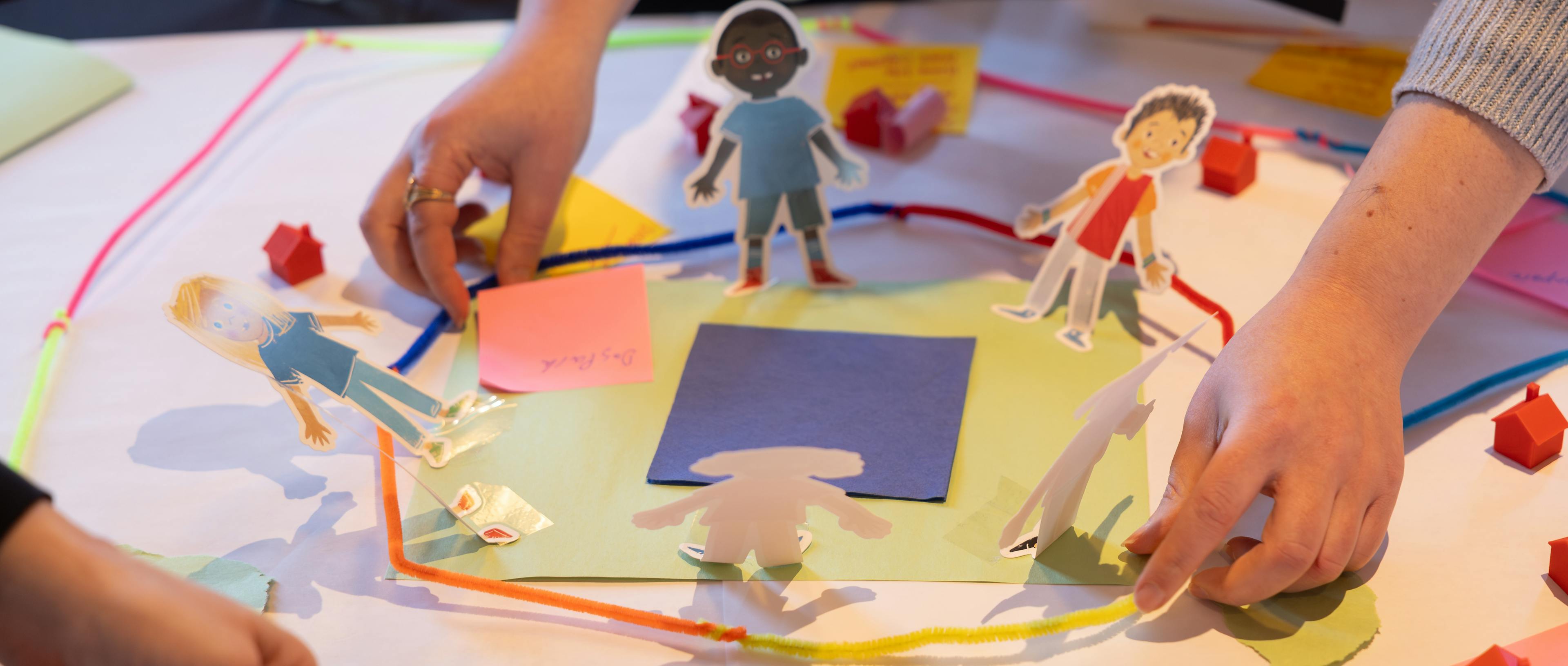 A diagram of a city made from pipe cleaners, pictures of people, and craft paper
