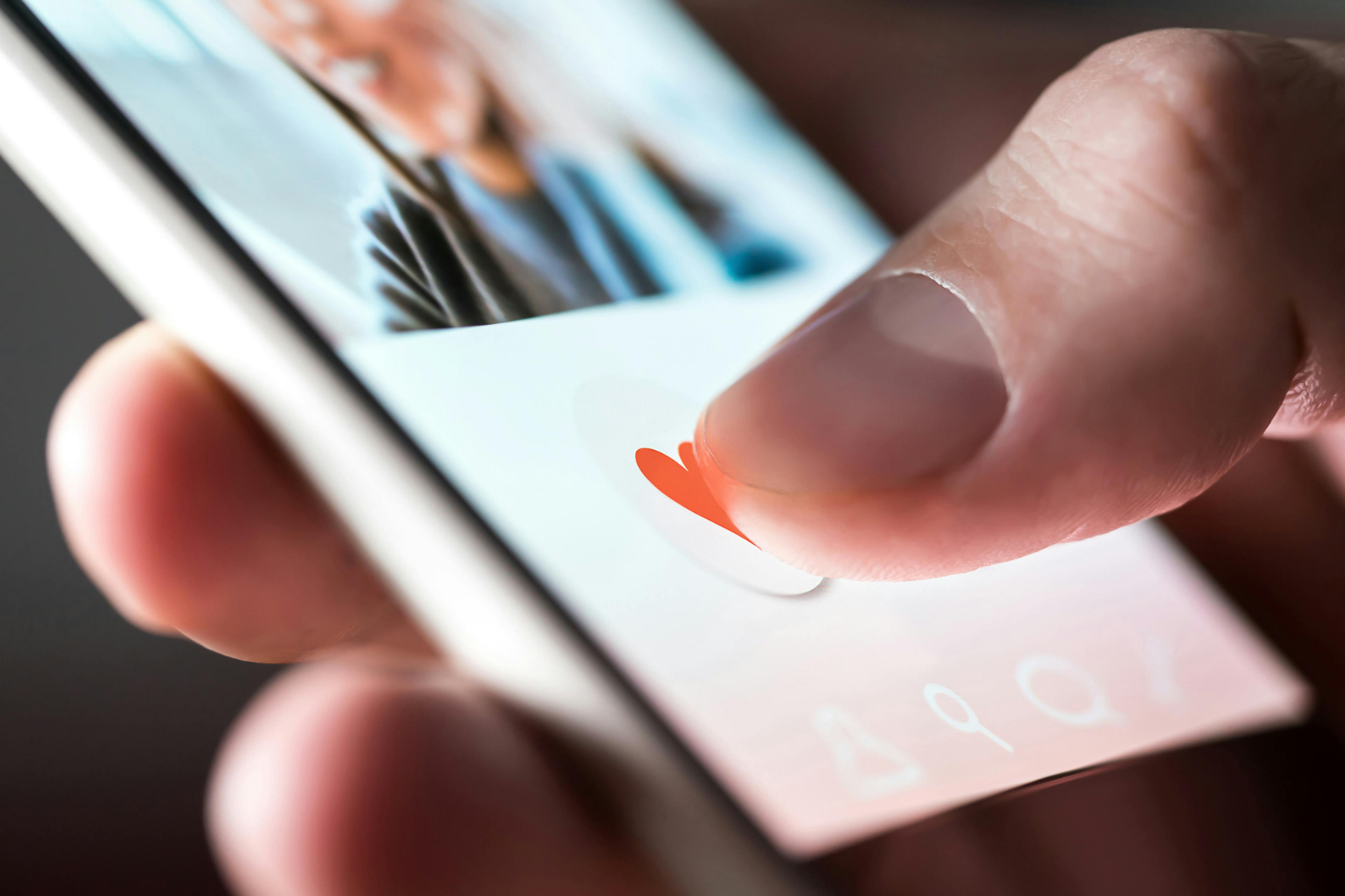 A smart phone with a thumb liking a post. 