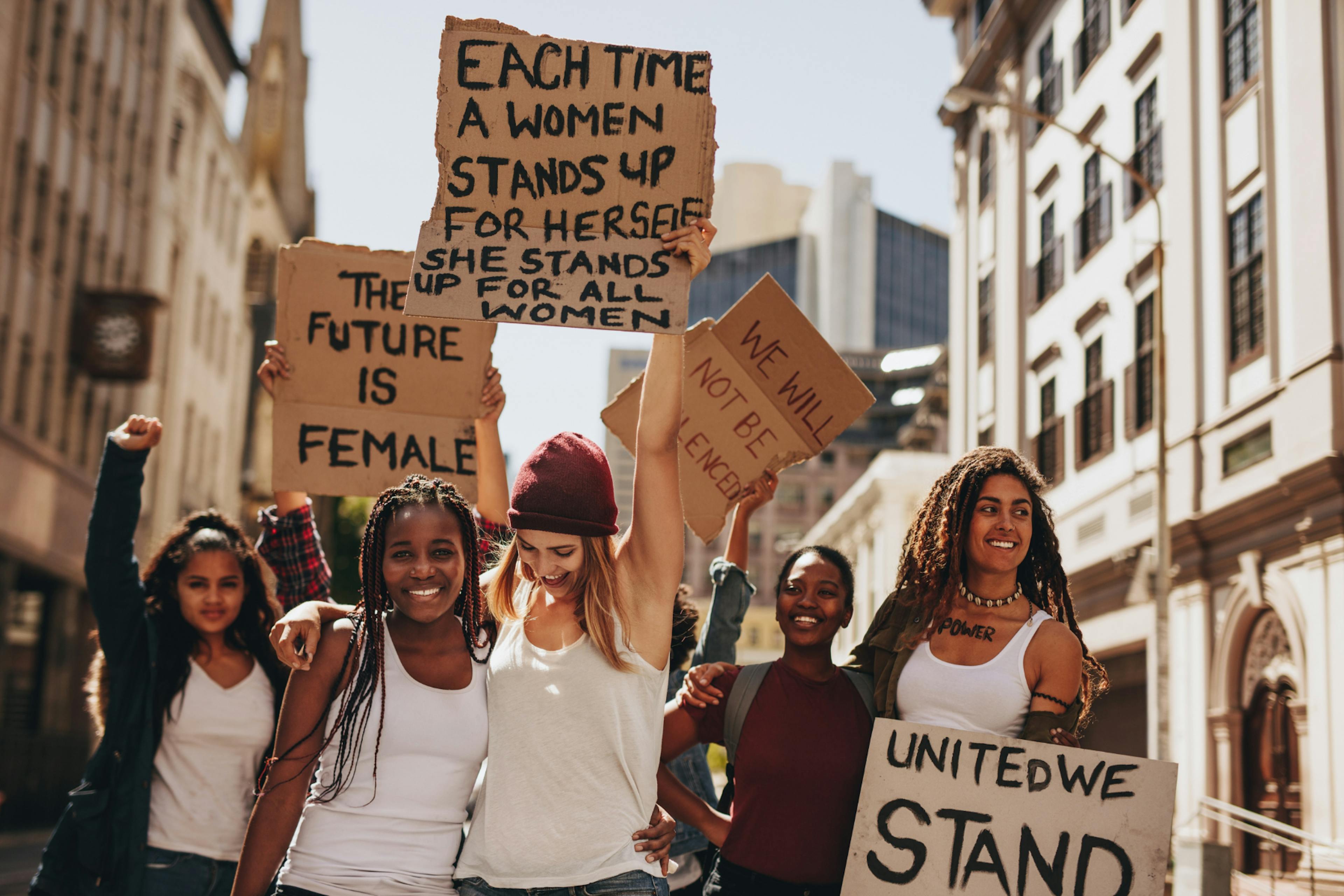 A group of women smiling and holding signs.