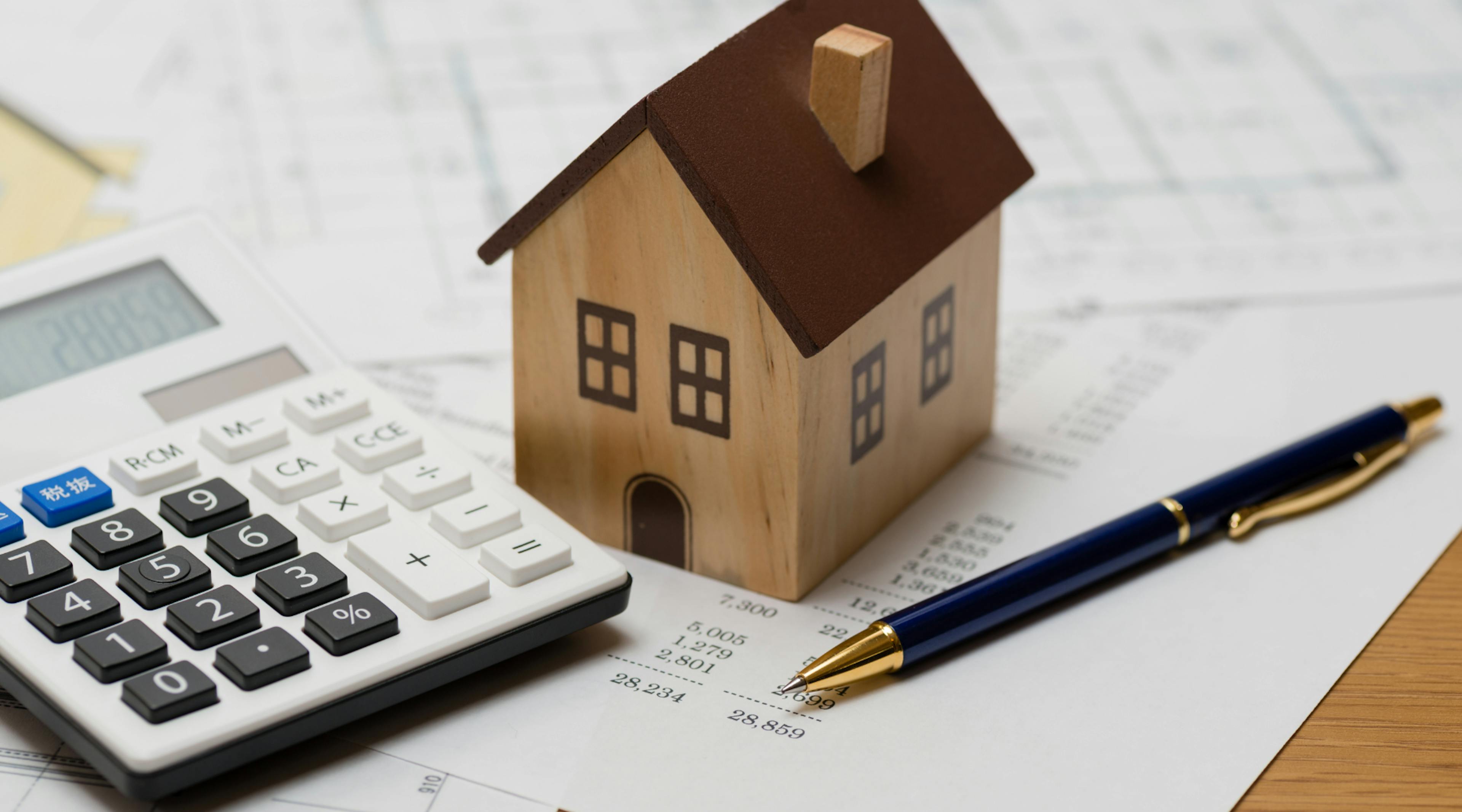 Toy house on top of papers with a calculator