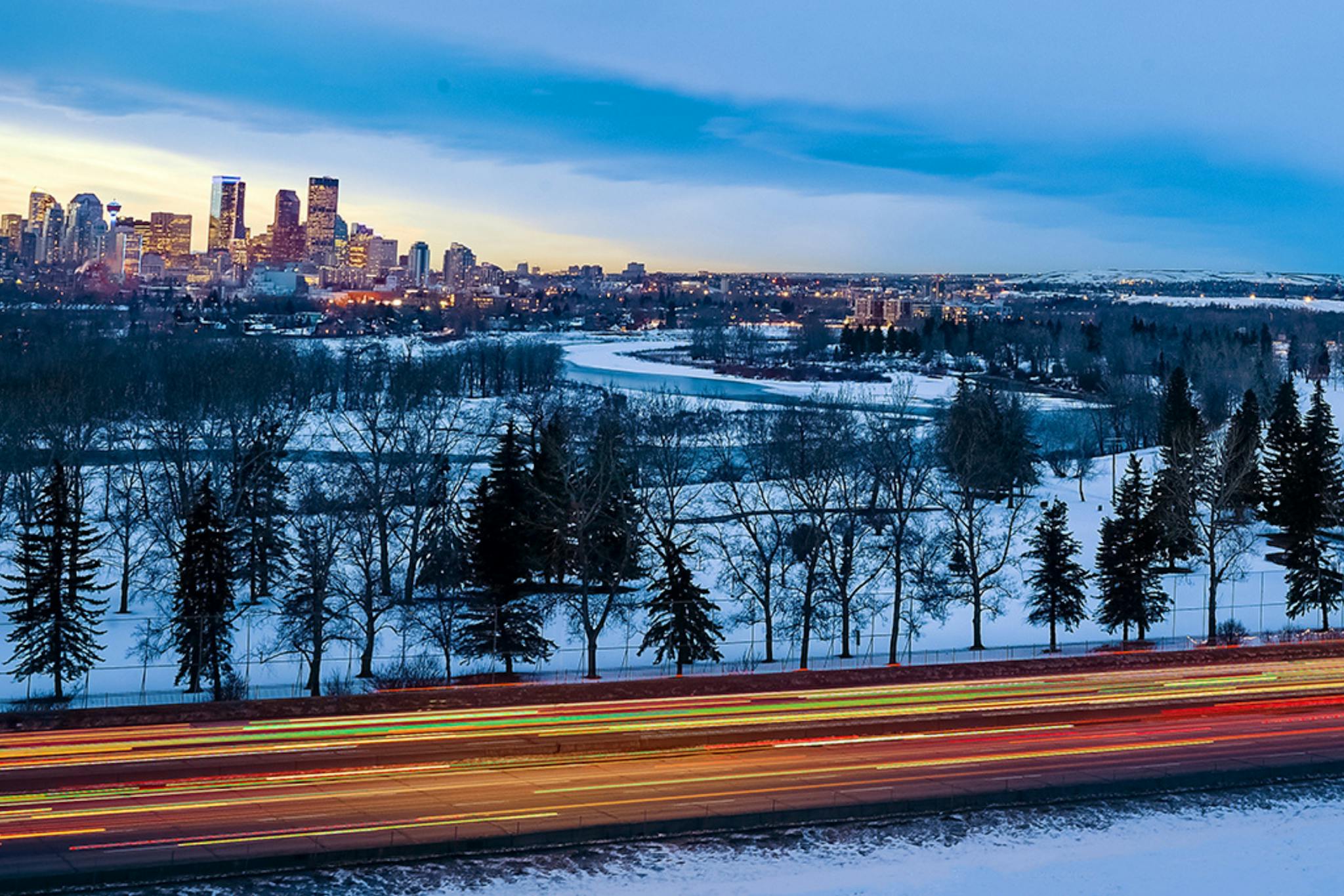 Winter picture of Calgary skyline at dusk with a road with car lights stretched showing fast traffic 