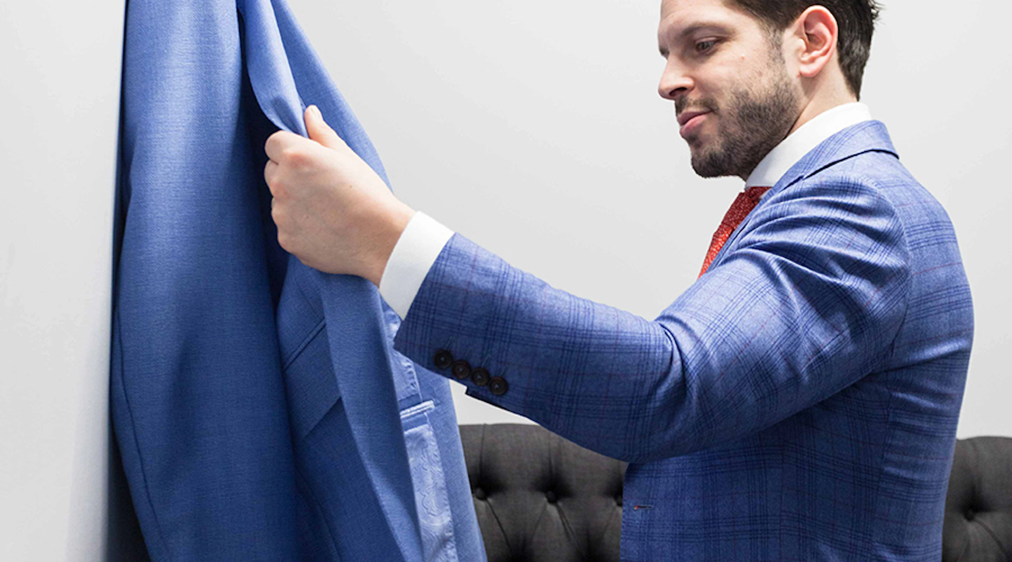 Man in suit examining another suit