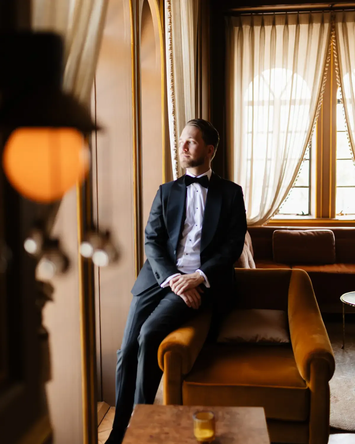 Groom in a custom Enzo Custom shawl-lapel tuxedo, seated by the window before the ceremony
