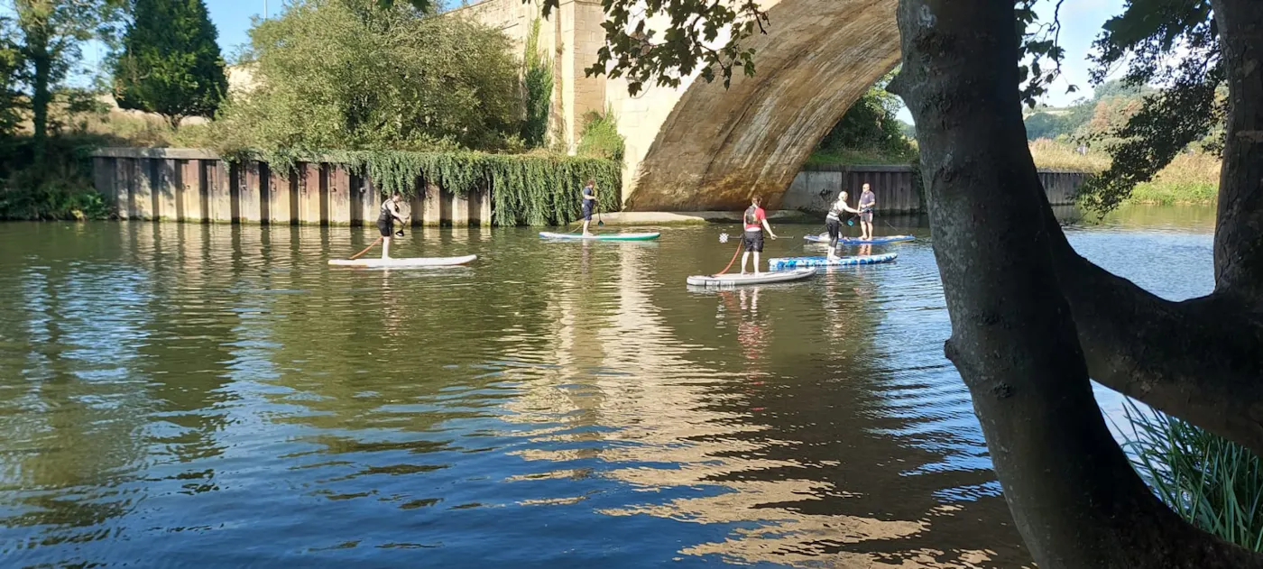 Paddleboarders on the River Avon beside a stone bridge near Bath