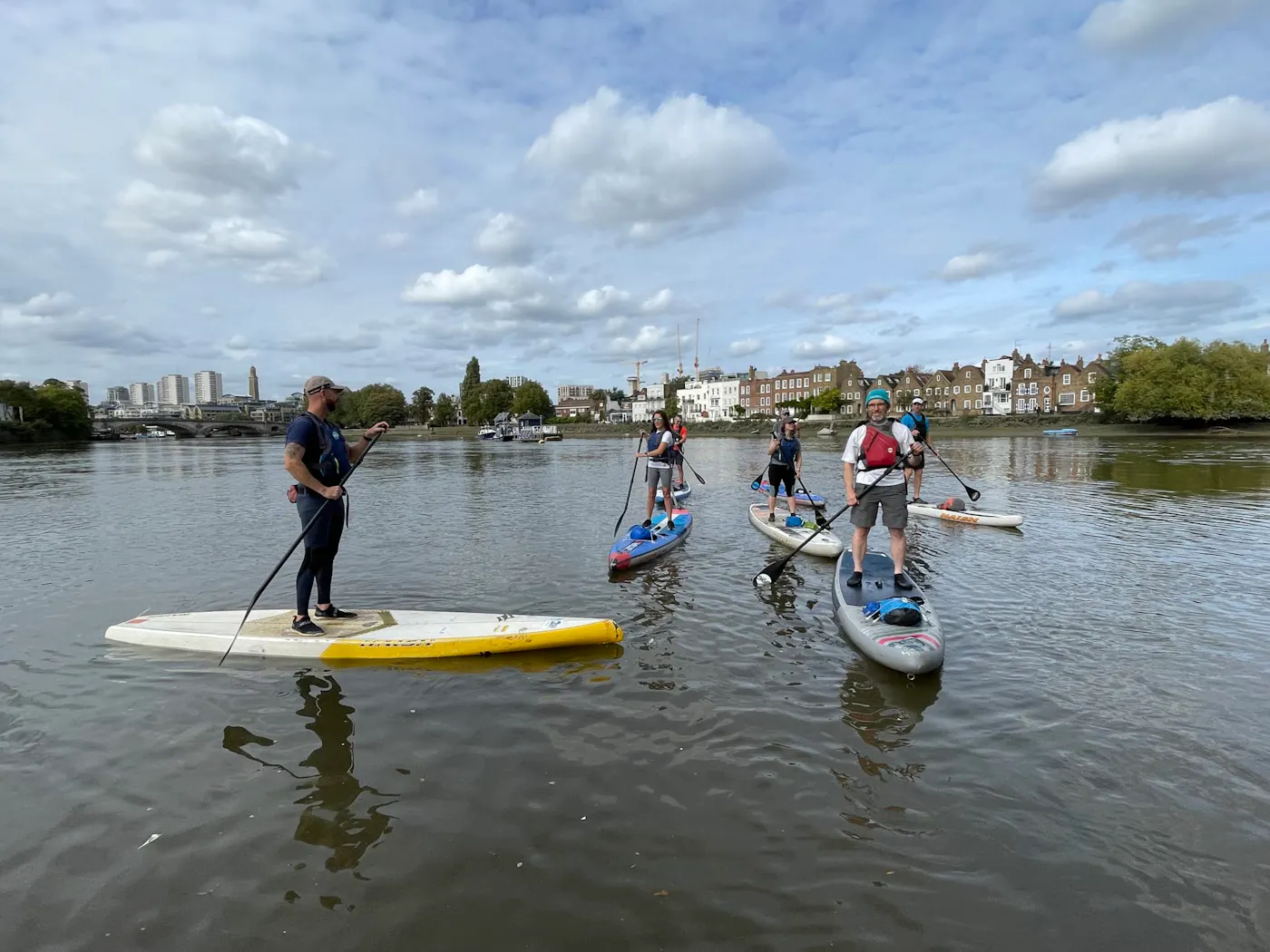 A group of paddleboarders standing on their boards on the River Thames in west London