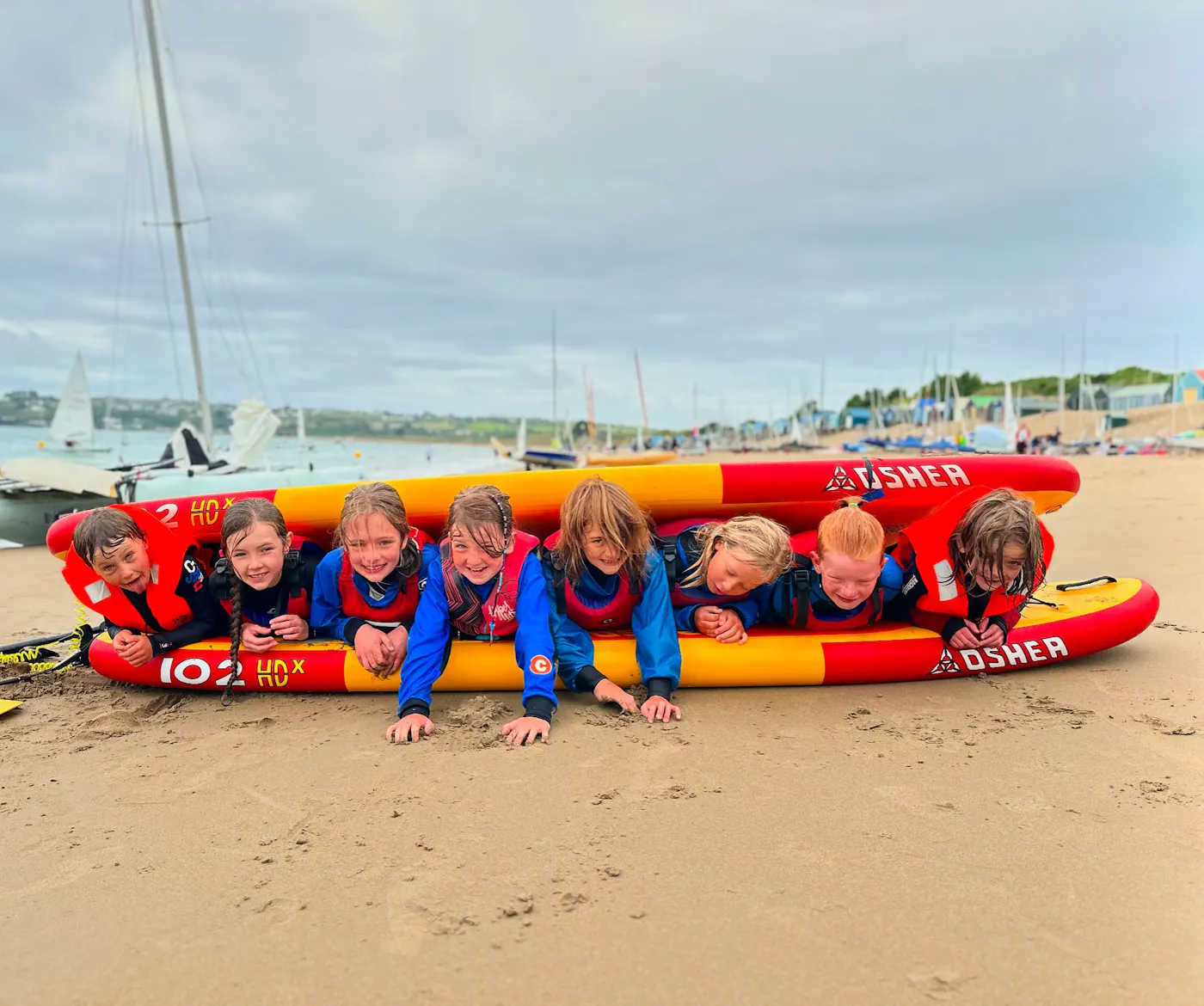 Children in buoyancy aids lying on an inflatable on Abersoch beach