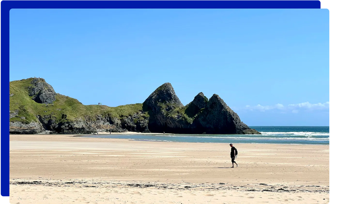 Walker on the beach at Three Cliffs Bay, Gower