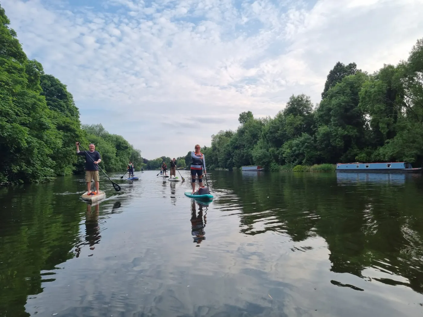 A group of paddleboarders on a calm, tree-lined stretch of the River Thames near Maidenhead