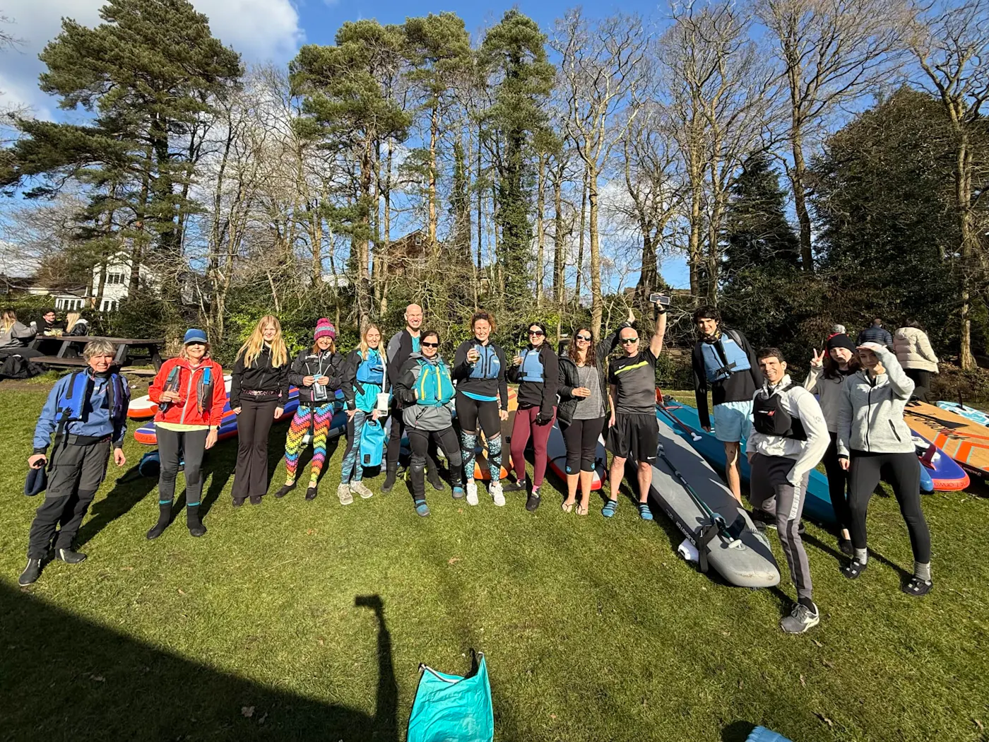 A group of paddlers with their boards gathered on the grass before a guided tour with Paddle SUP Company